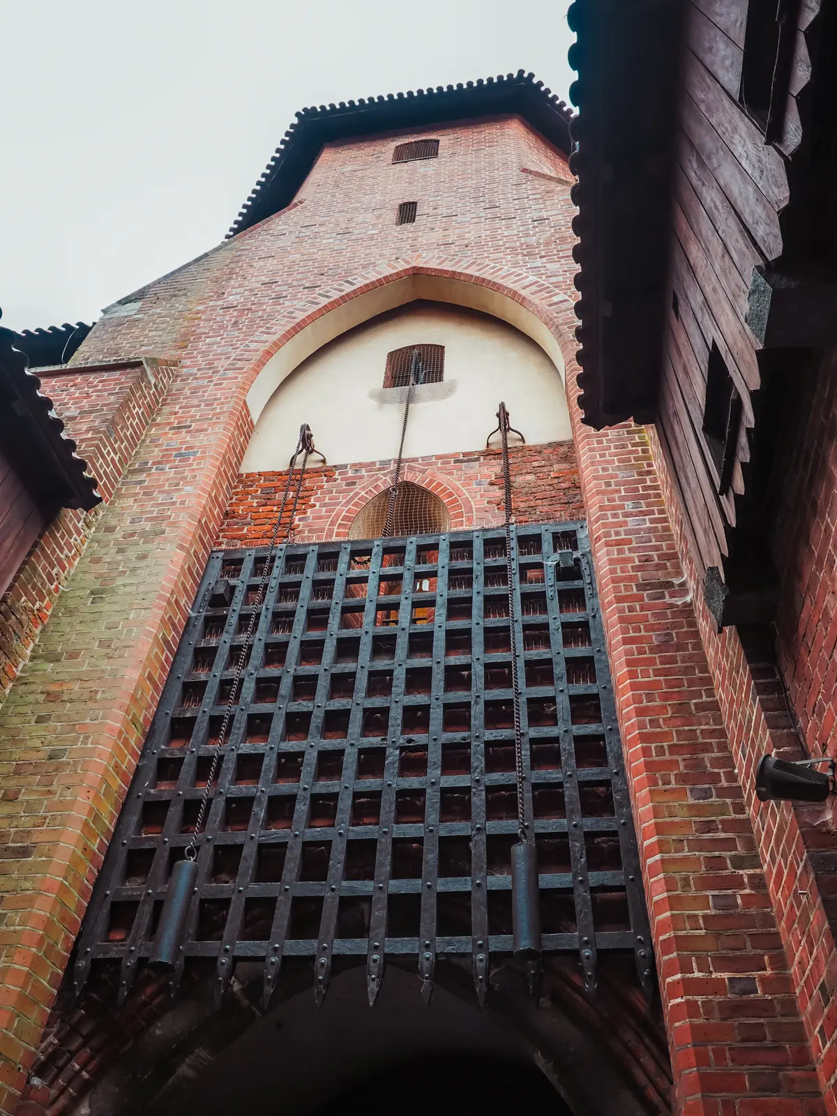 Tall black metal gate at the red brick Malbork Castle.