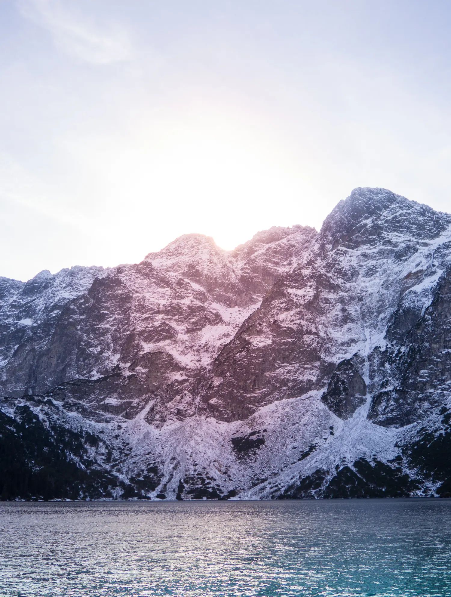 Close up of sun going down behind snow clad mountains behind Morskie Oko Lake in southern Poland. Krakow to Morkie Oko.