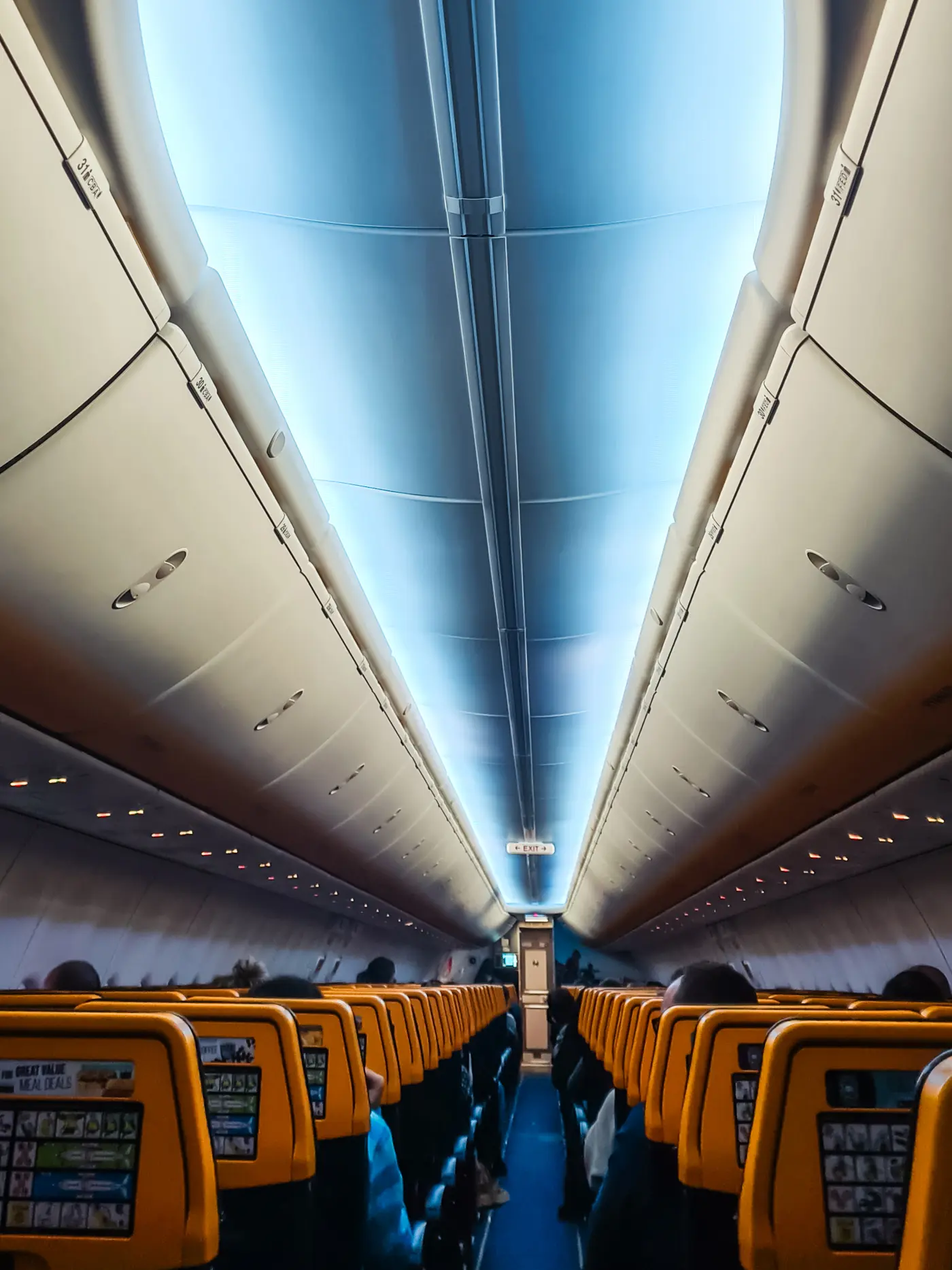 Inside new Ryanair plane, looking down the aisle,  with light in the ceiling and rows of yellow headrests. My experience with Ryanair.