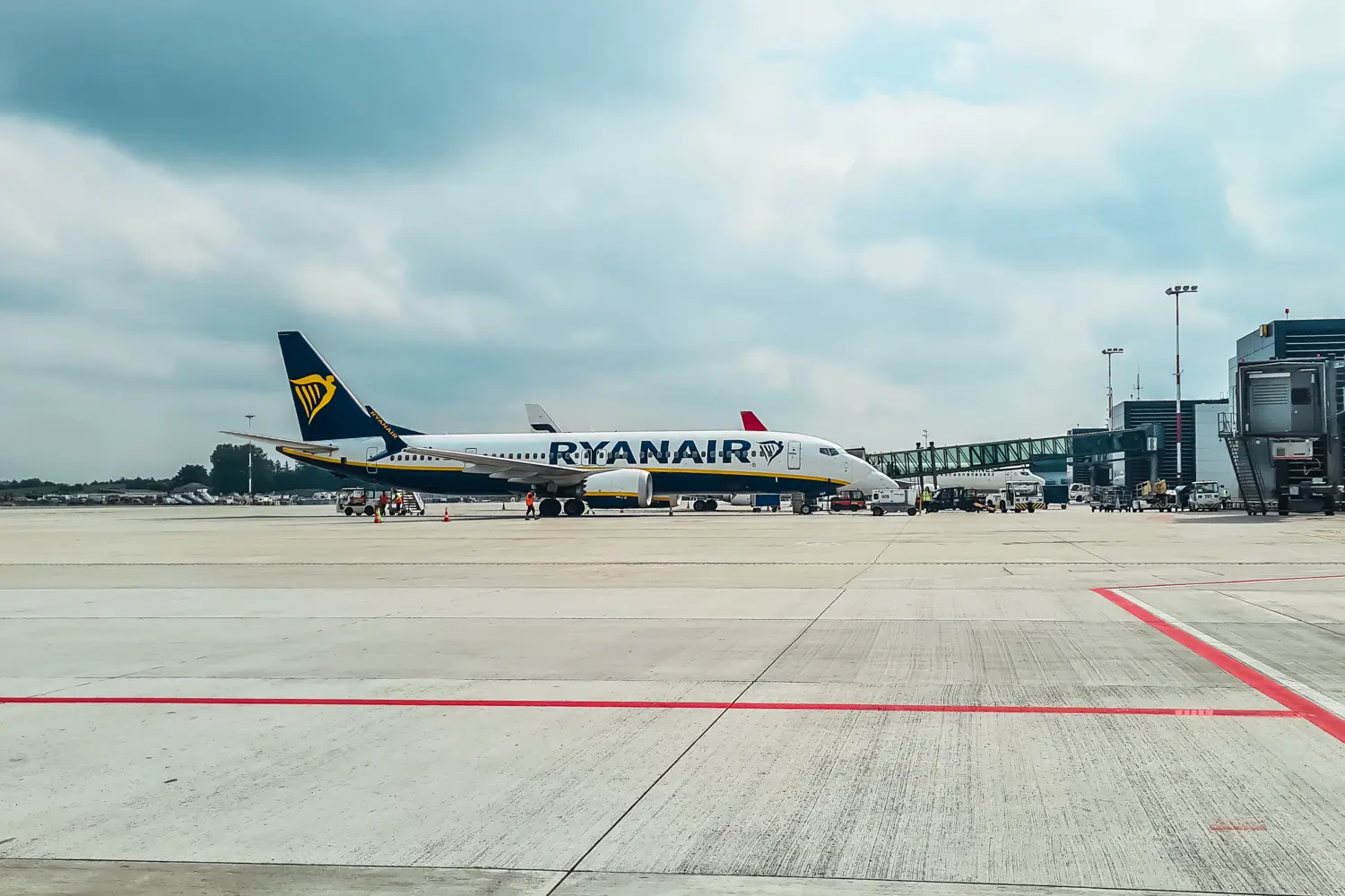 White Ryanair plane with blue tail by the gate at the airport on a cloudy day. Ryanair honest review.