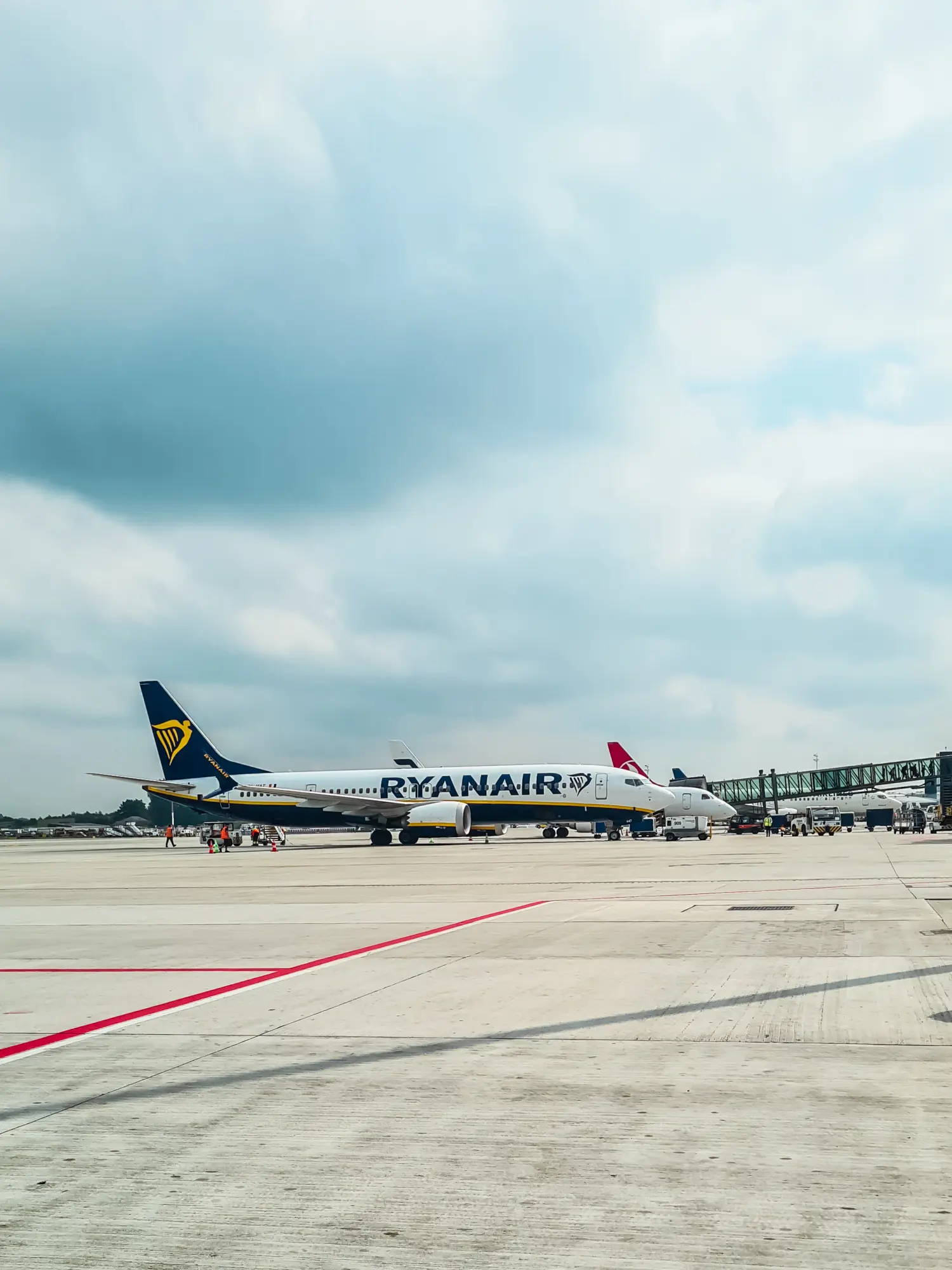 White Ryanair plane with blue tail by the gate at the airport on a cloudy day. Ryanair honest review.