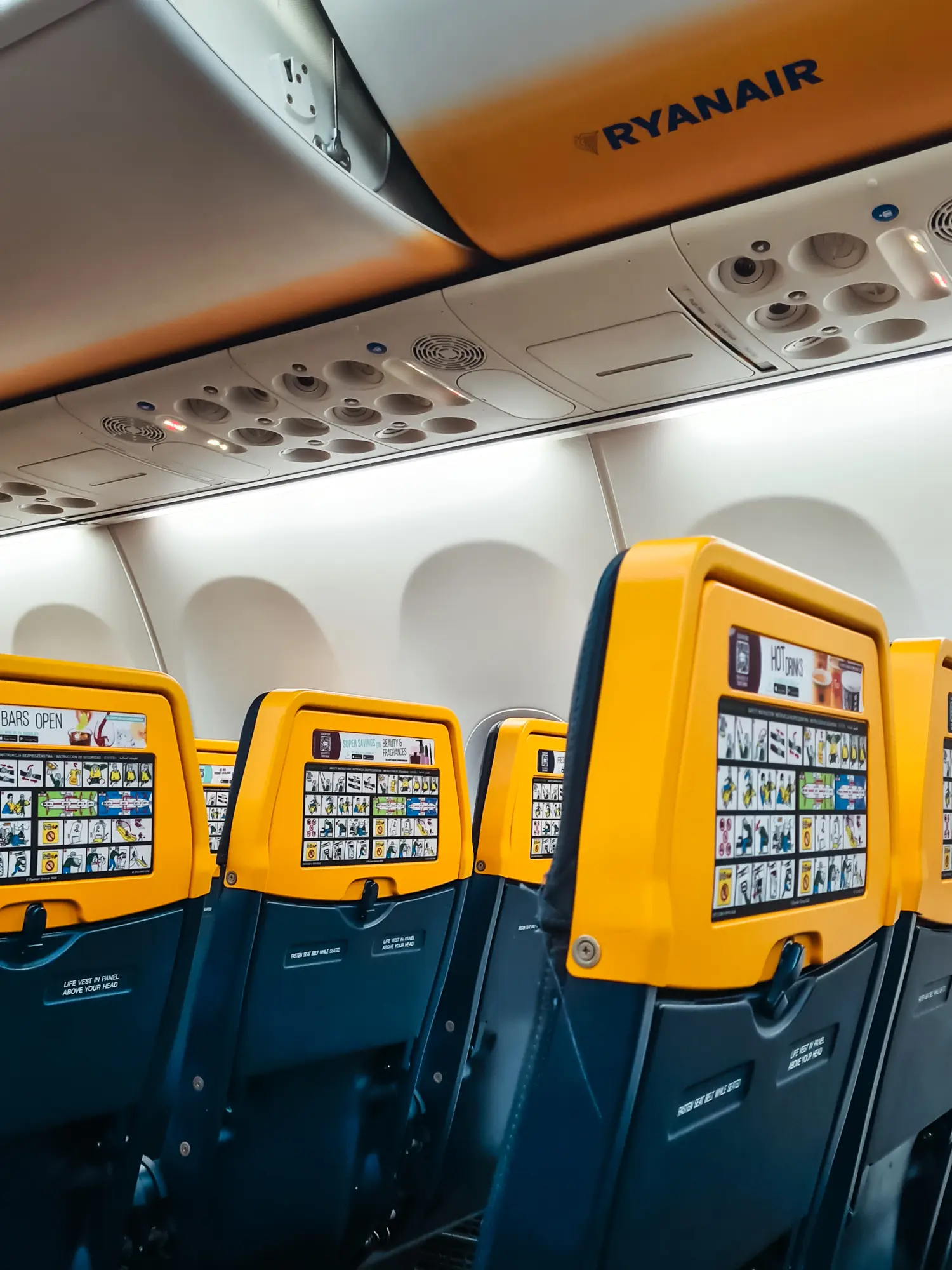 Dark blue seats with yellow headrests inside an empty Ryanair plane.