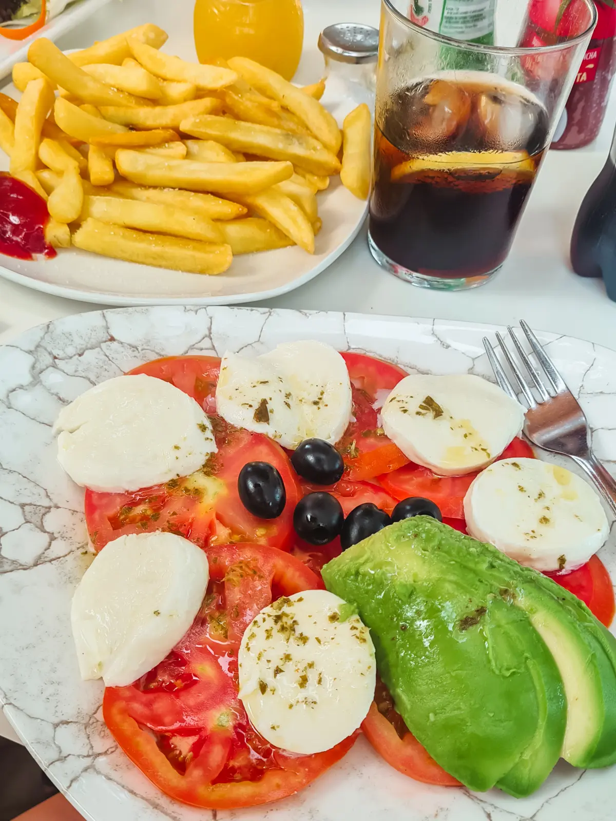 Slices of tomato, mozzarella and avocado on a white plate at Sa Font de n'Alis restaurant in Cala Mondrago, Mallorca.