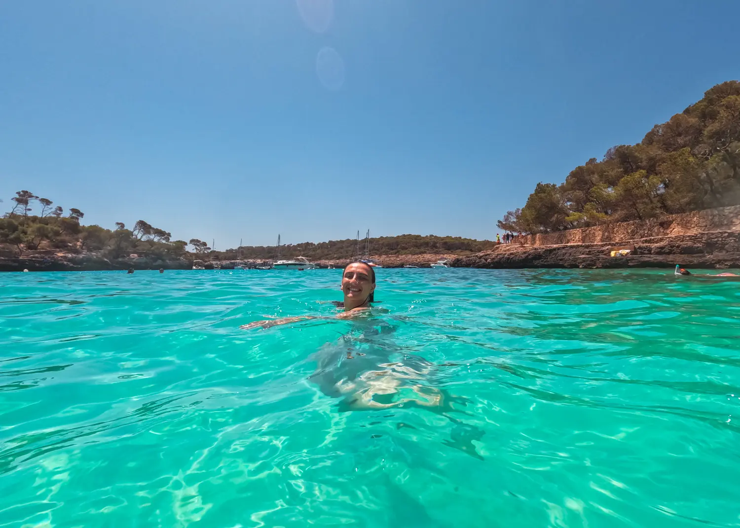 Girl smiling while swimming in the turquoise ocean of Cala Mondrago in Mondrago Natural Park in Mallorca.