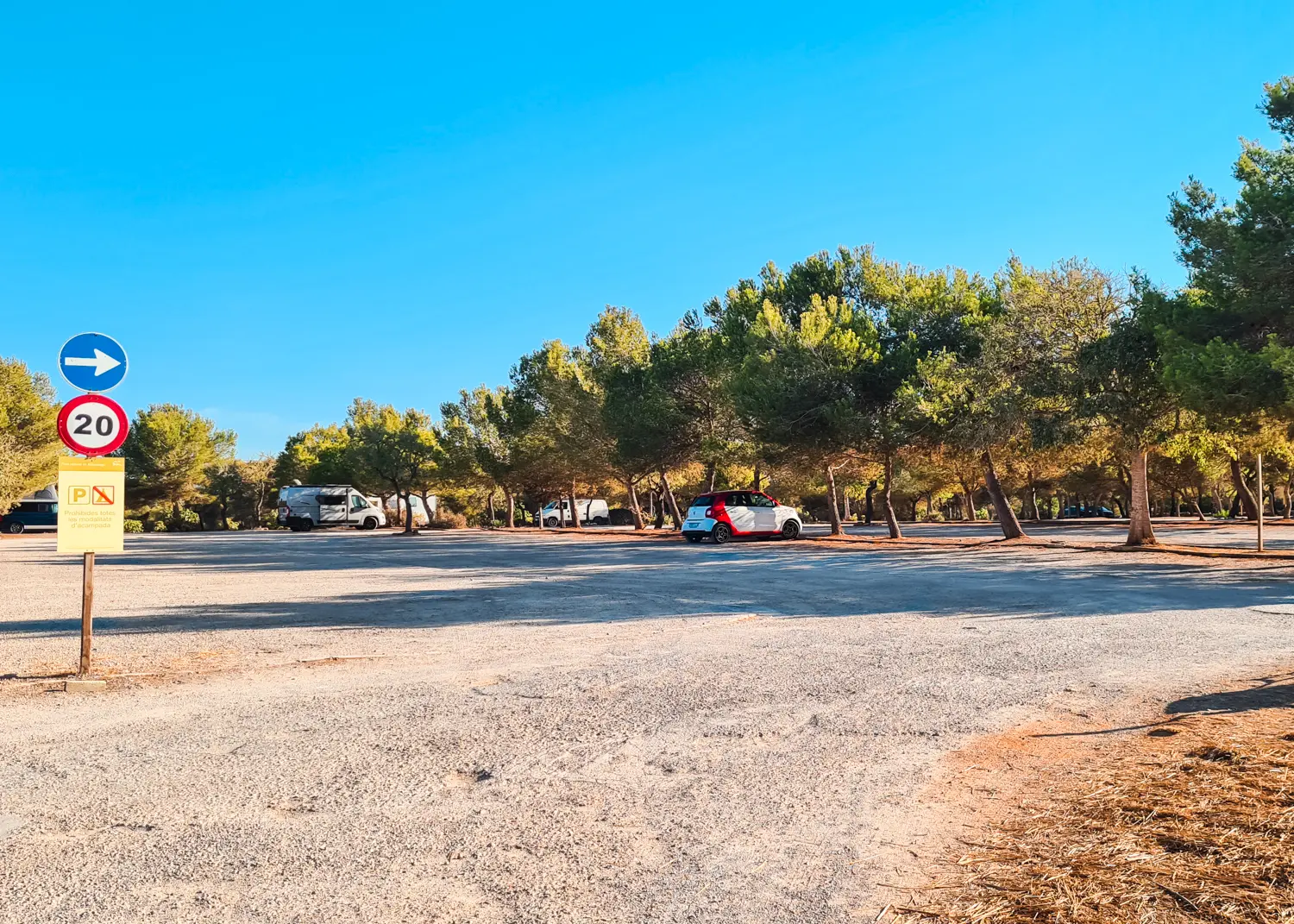 One van and a white car at a vacant gravel parking lot atCala S'Amarador in Mondrago Natural Park in Mallorca.