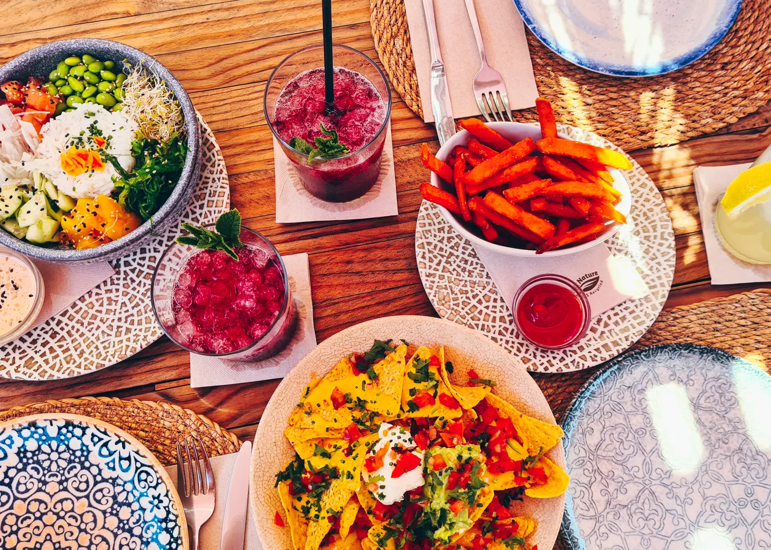 Two pink drinks with ice and three plates of food seen form above at Retroway, one of the best caf&eacute;s in Santanyi Mallorca.