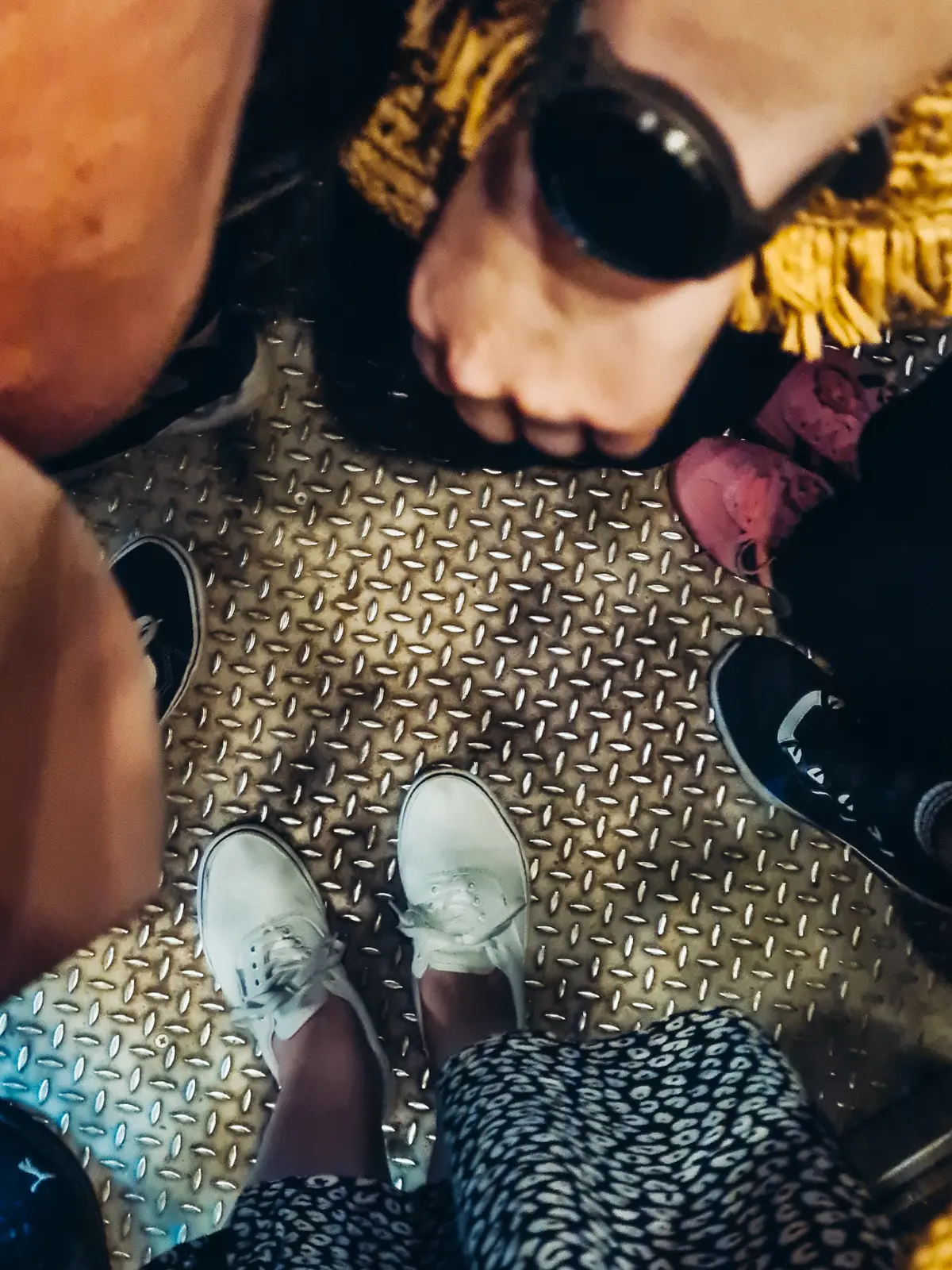 View from above of many feet standing on a metal floor in the elevator in Wieliczka Salt Mine.