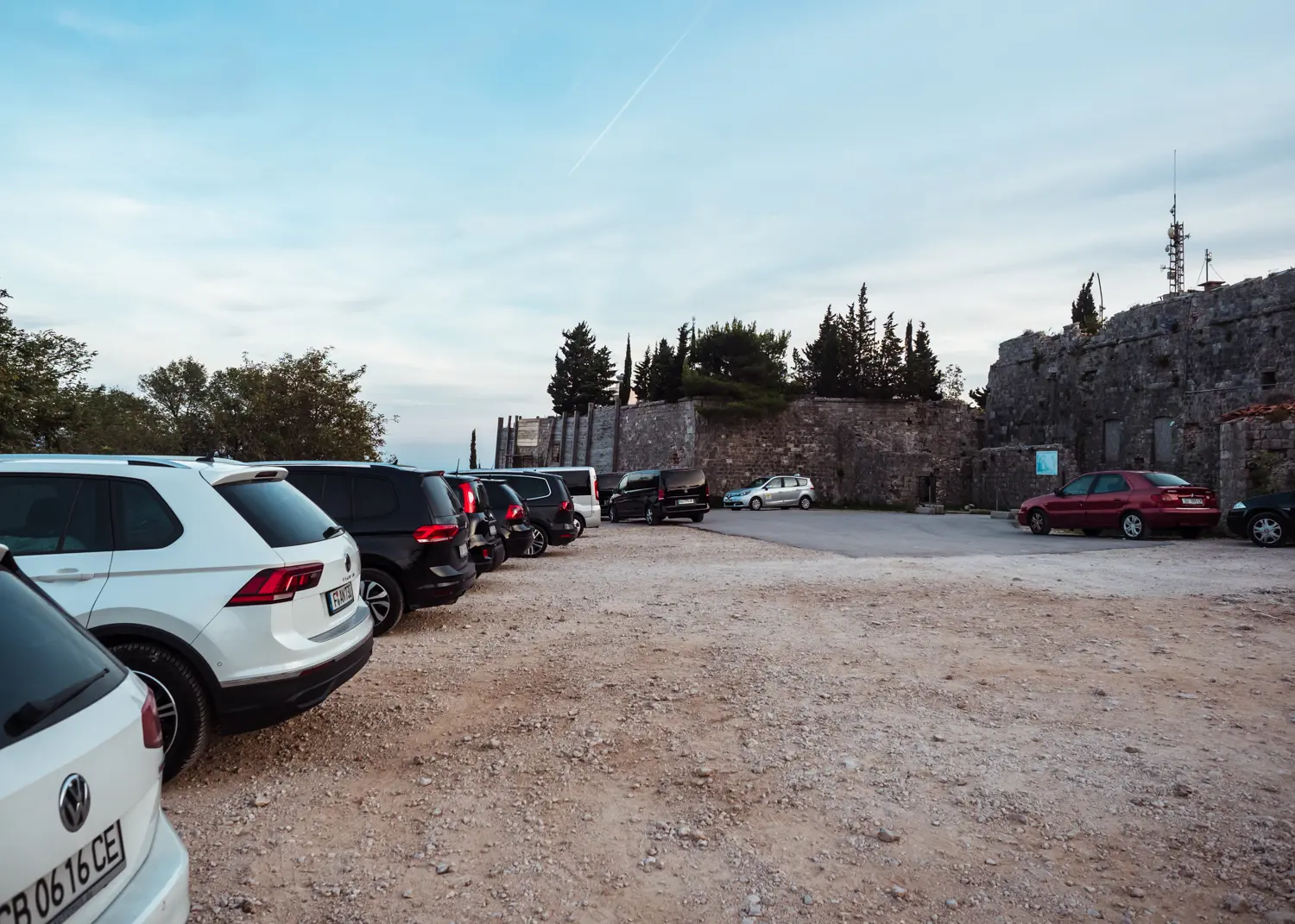 Black and white cars lined up on a dirt parking lot with Fort Imperial in the background on Mount Srd in Dubrovnik. How to get there by car.