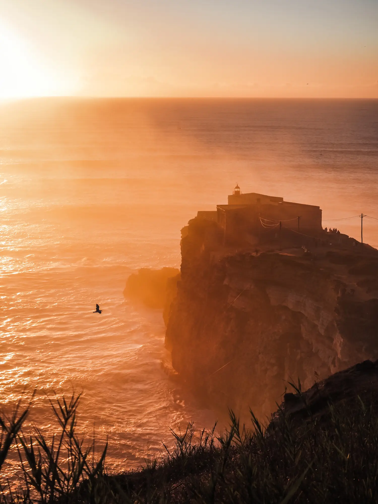 View from atop a hill of São Miguel Arcanjo Fort on a rocky outcrop in the ocean of Nazare, Portugal at sunset.