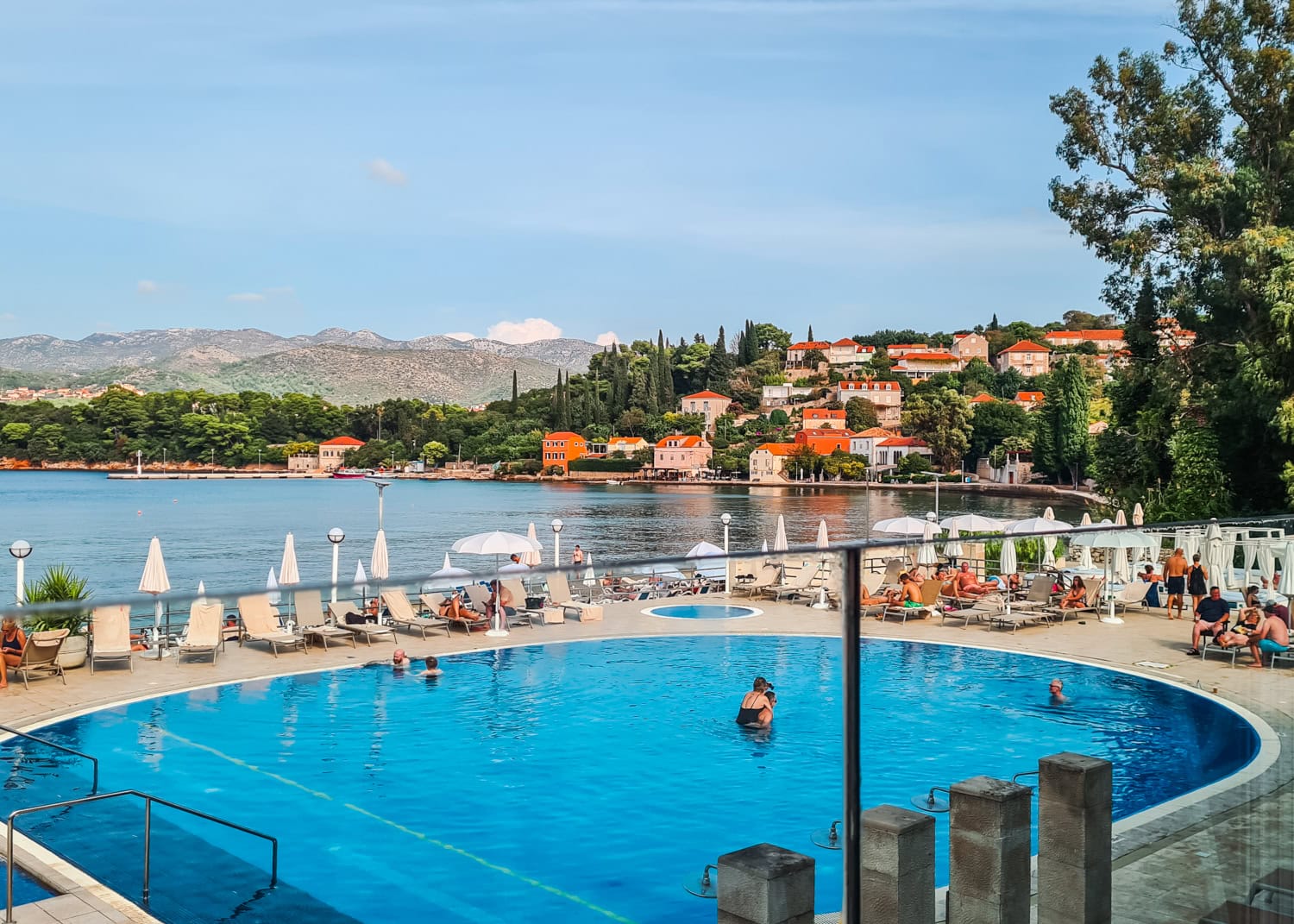 Round turquoise pool with sunbeds and white parasols around it by the beach at TUI BLUE Kalamota Island Resort Kolocep Island Dubrovnik review.