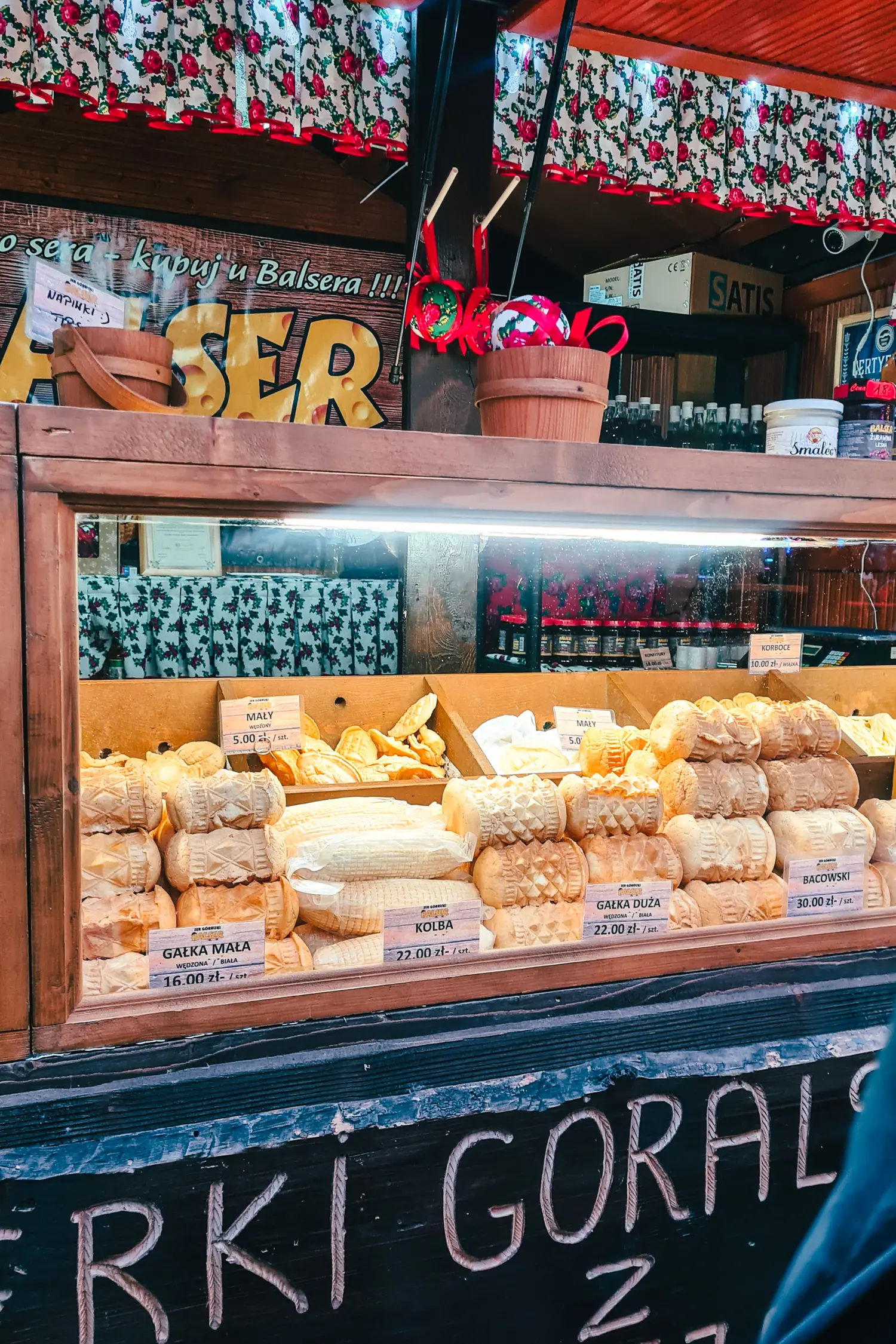 Lit up glass display with wooden frame of traditional Polish cheese Oscypek in different shapes and sizes at Wroclaw Christmas Market.