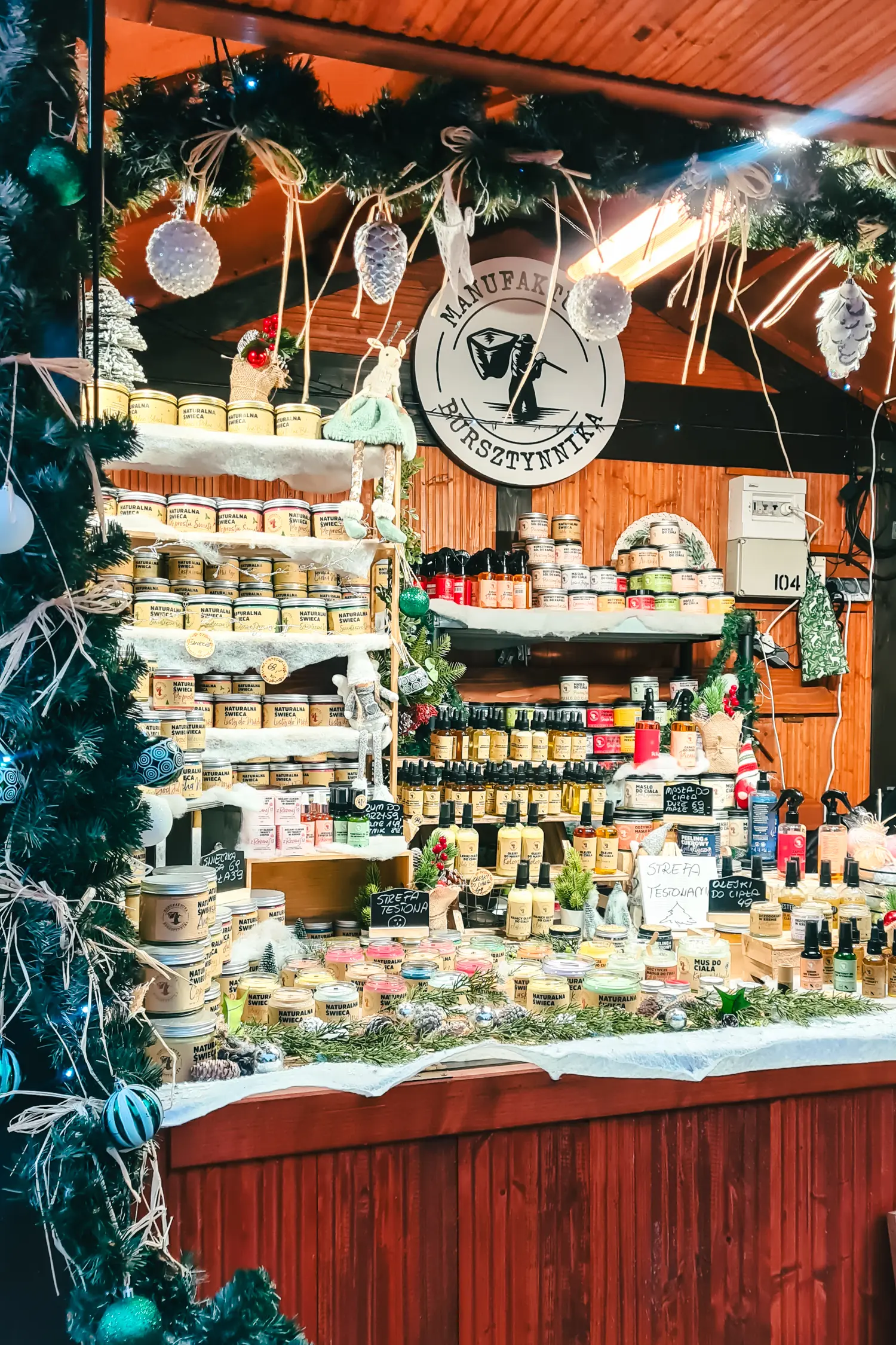 Wooden stall decorated with garland selling candles and oils at Wroclaw Christmas Market.