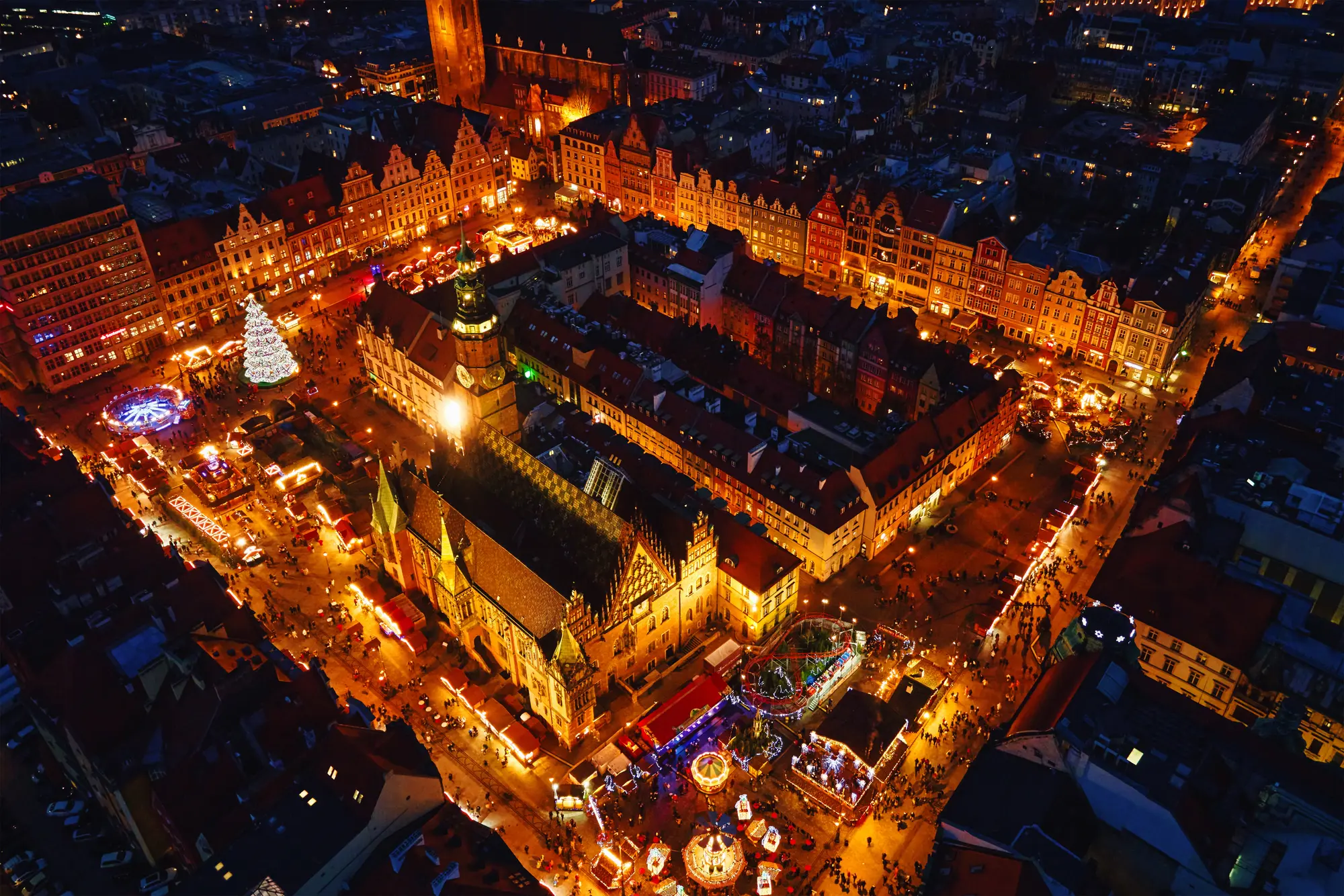 Night view from above of Wroclaw Christmas Market set on the square Rynek surrounded by old town houses all lit up.