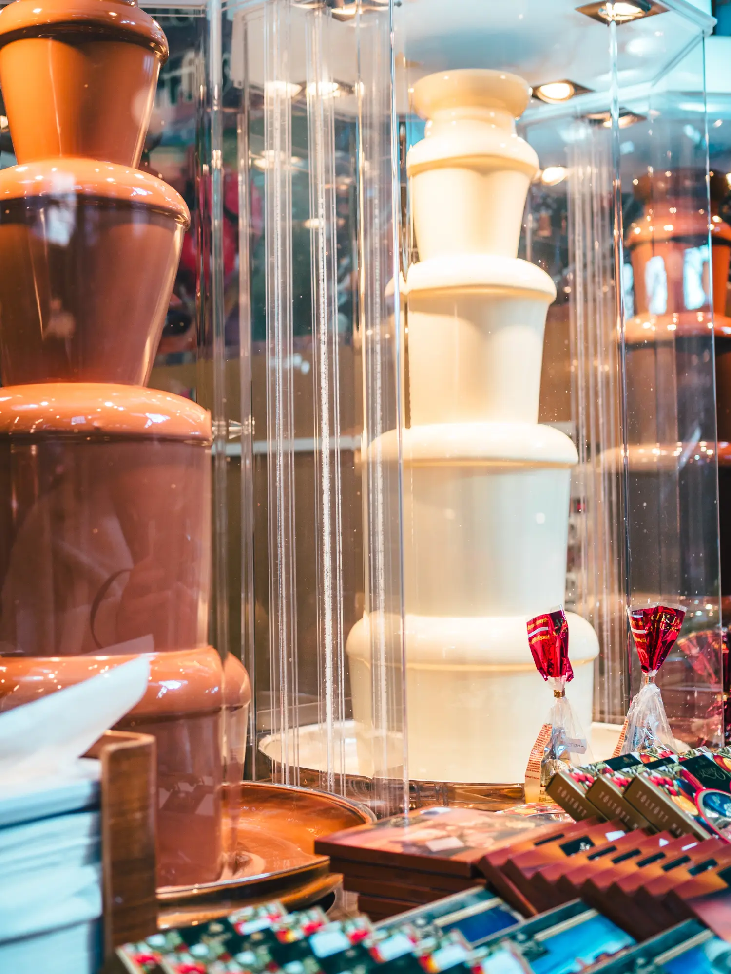Close up of two chocolate fountains, one white and one brown, in a glass display at the food court in the Central Market Hall in Budapest.