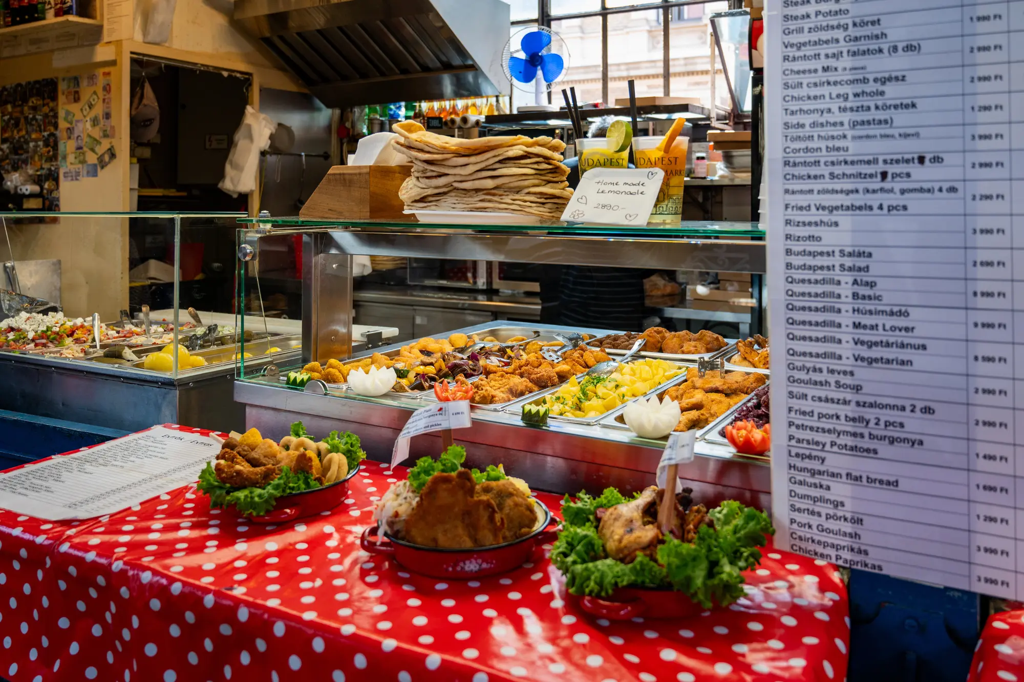 Three dishes on display on a red table cloth in front of a food stall at the Central Market Hall in Budapest.