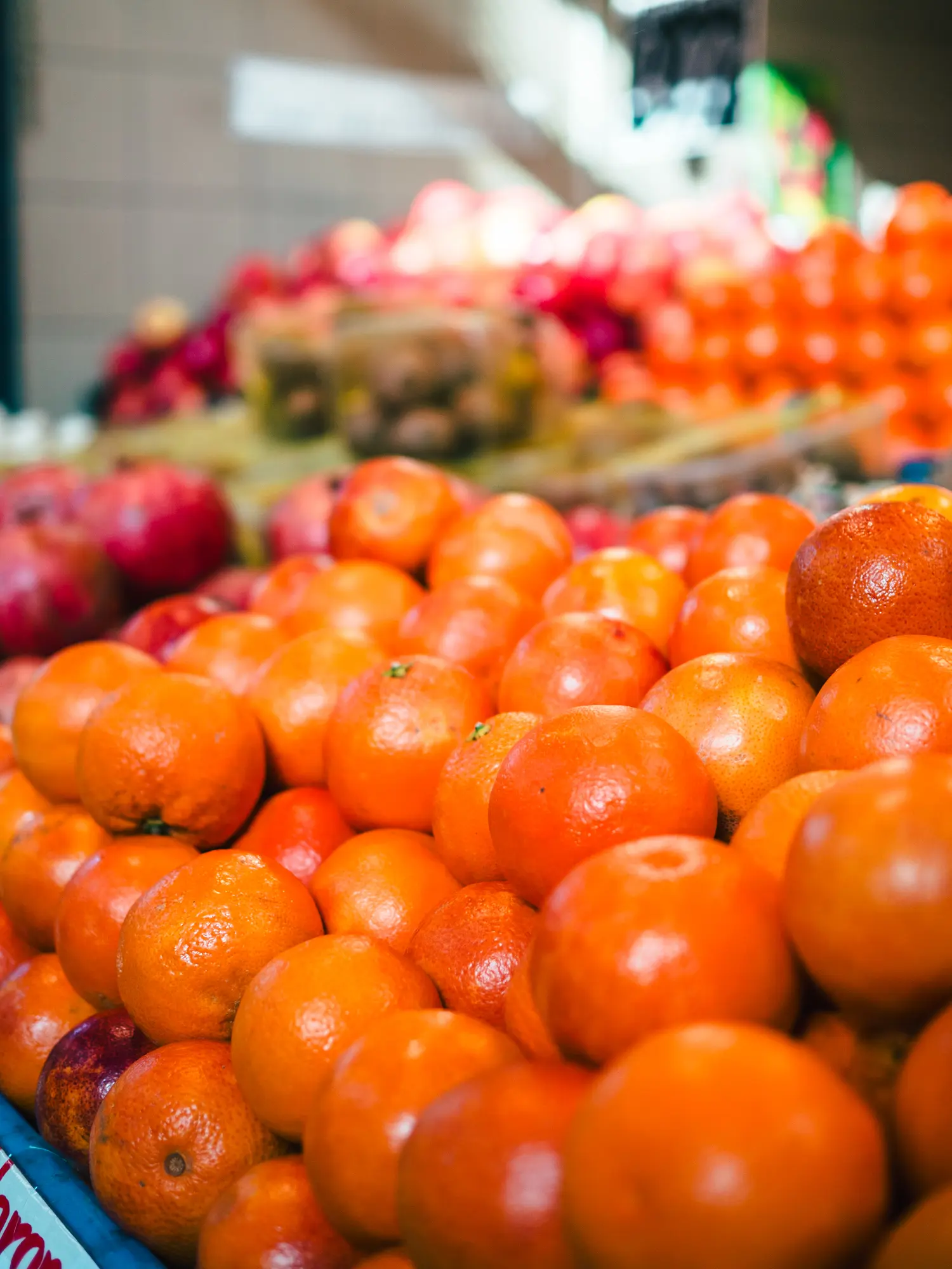 Close up of a stack of orange clementines with other fruit in the background while shopping at Budapest Central Market Hall.