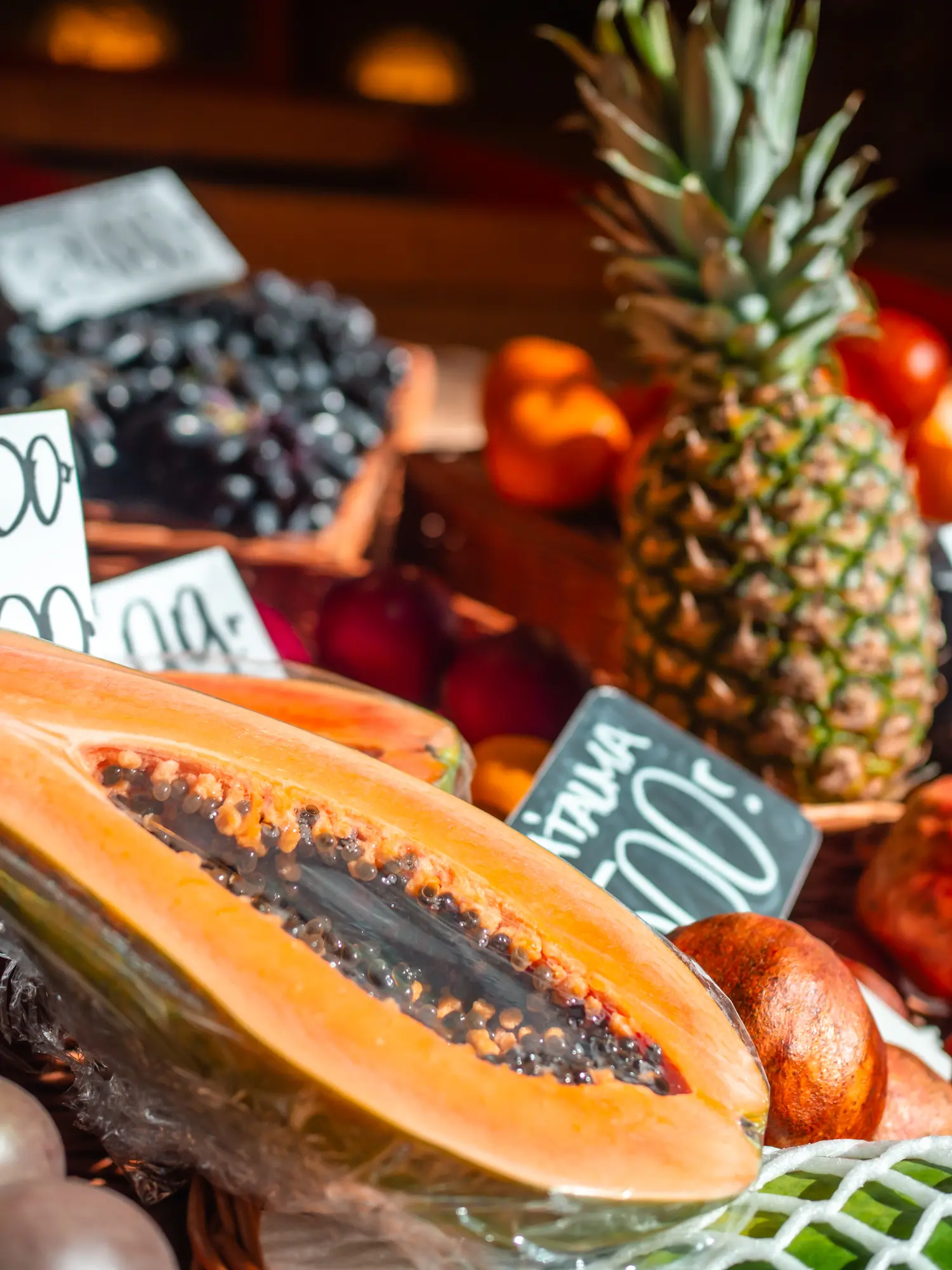 Close up of a pineapple, half a papaya and other fruit in the background at a stall in Budapest Central Market Hall