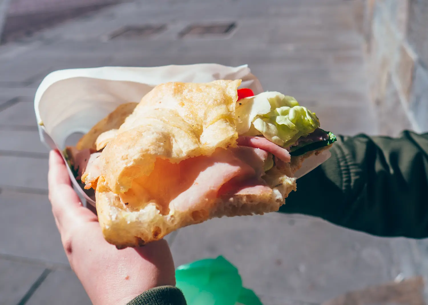 Close up of two hands holding a large, delicious focaccia with ham, cheese and lettuce from Il Fornaio in Bergamo, Italy.