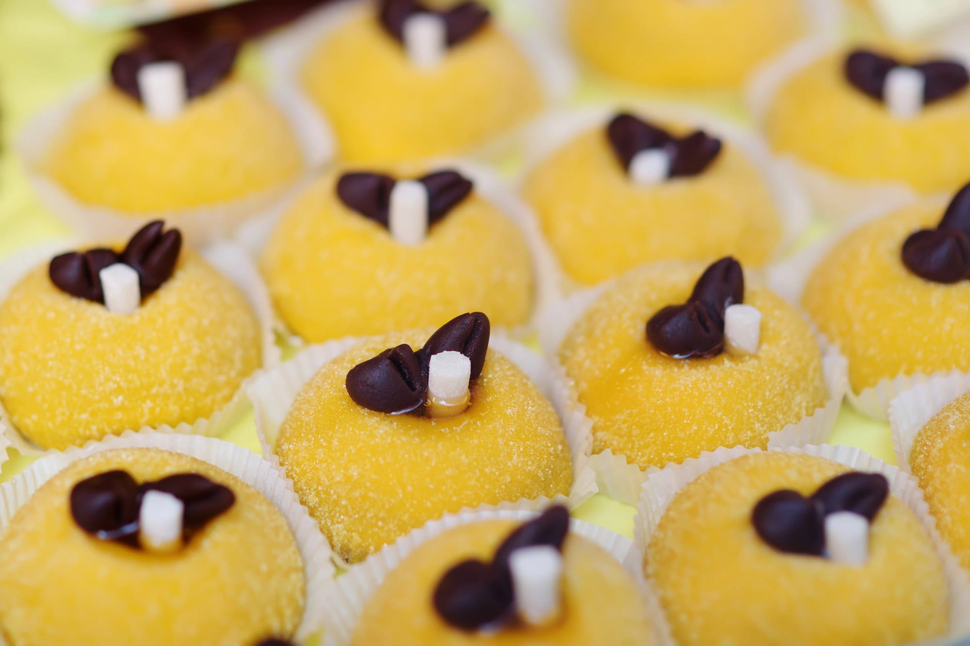 Close up of a tray of Polenta e Osei, a traditional small yellow cake topped with chocolate popular in Bergamo.