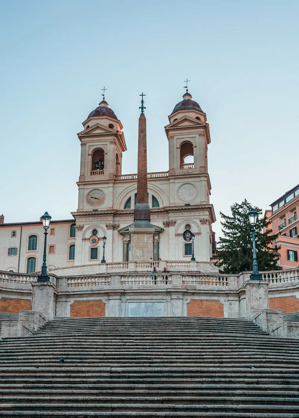 Famous steps with a monument and church in the background at Piazza di Spagna, one of the most luxurious areas to stay in Rome.