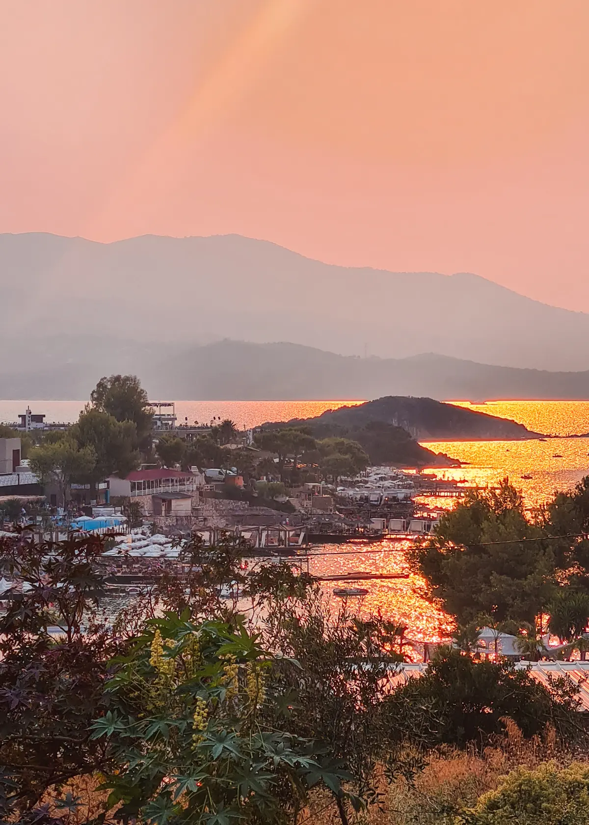 Pink and orange sunset view of the beaches, islands and glistening ocean in Ksamil taken from Casa Mexicana Restaurant terrace.