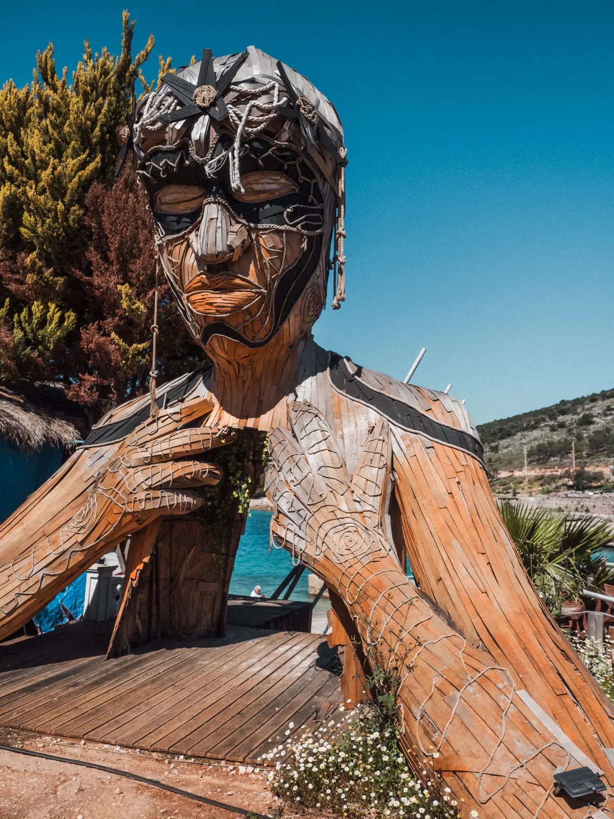 Large head and hands made from straw covering the entrance to a beach club in Ksamil.