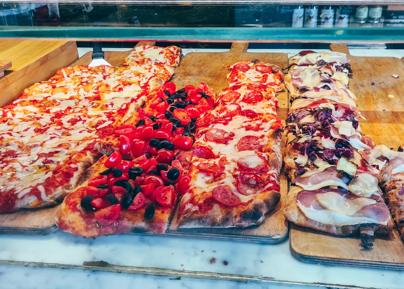 Close up of a display of pizza sized with tomato and cheese topping in a café close to the Leaning Tower of Pisa.