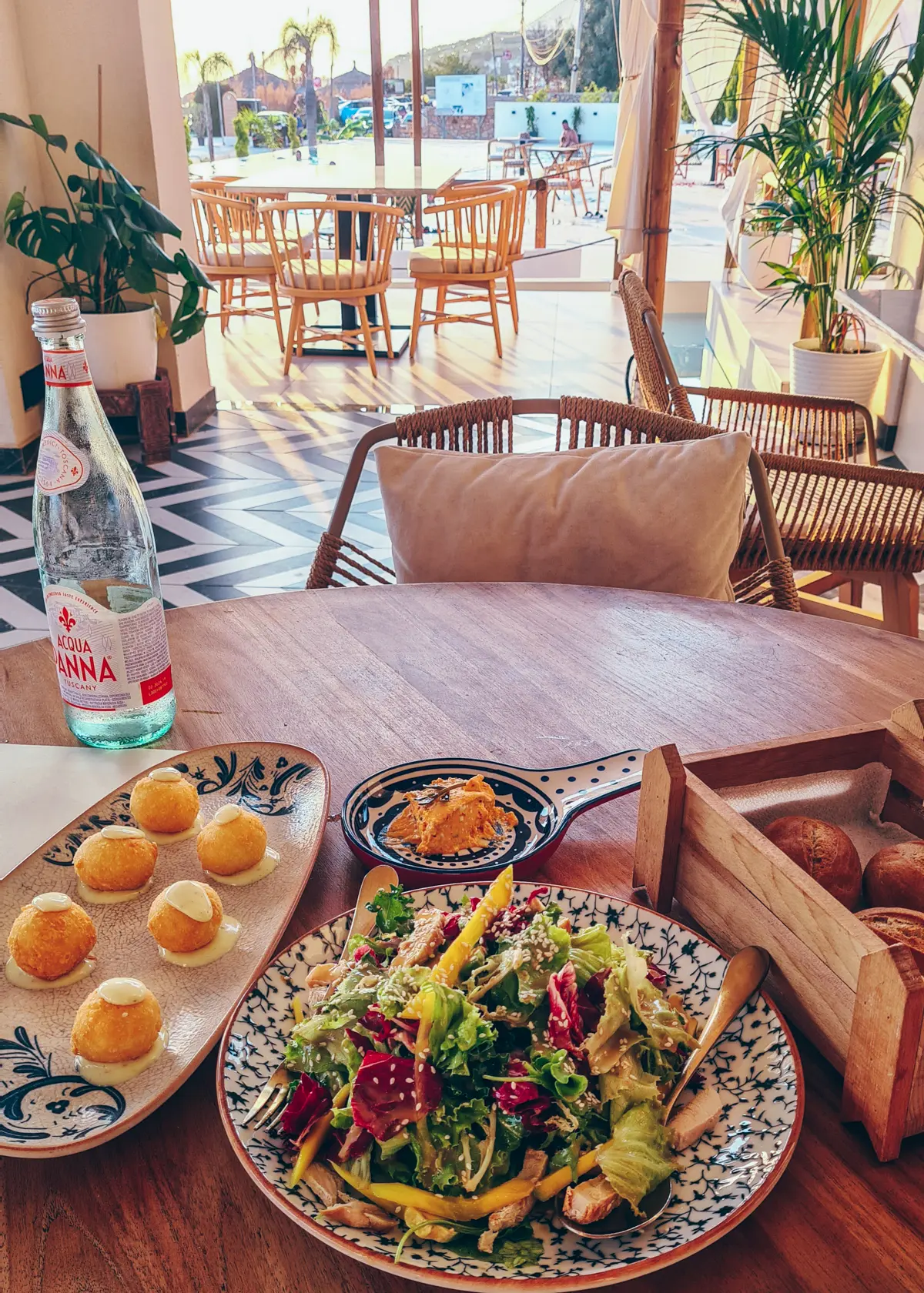 mango and chicken salad on a blue and white patterned plate, six fried cheese balls on a blue and white patterned plate and a wooden bread basket on a table at Abonora Restaurant in Drymades Beach.