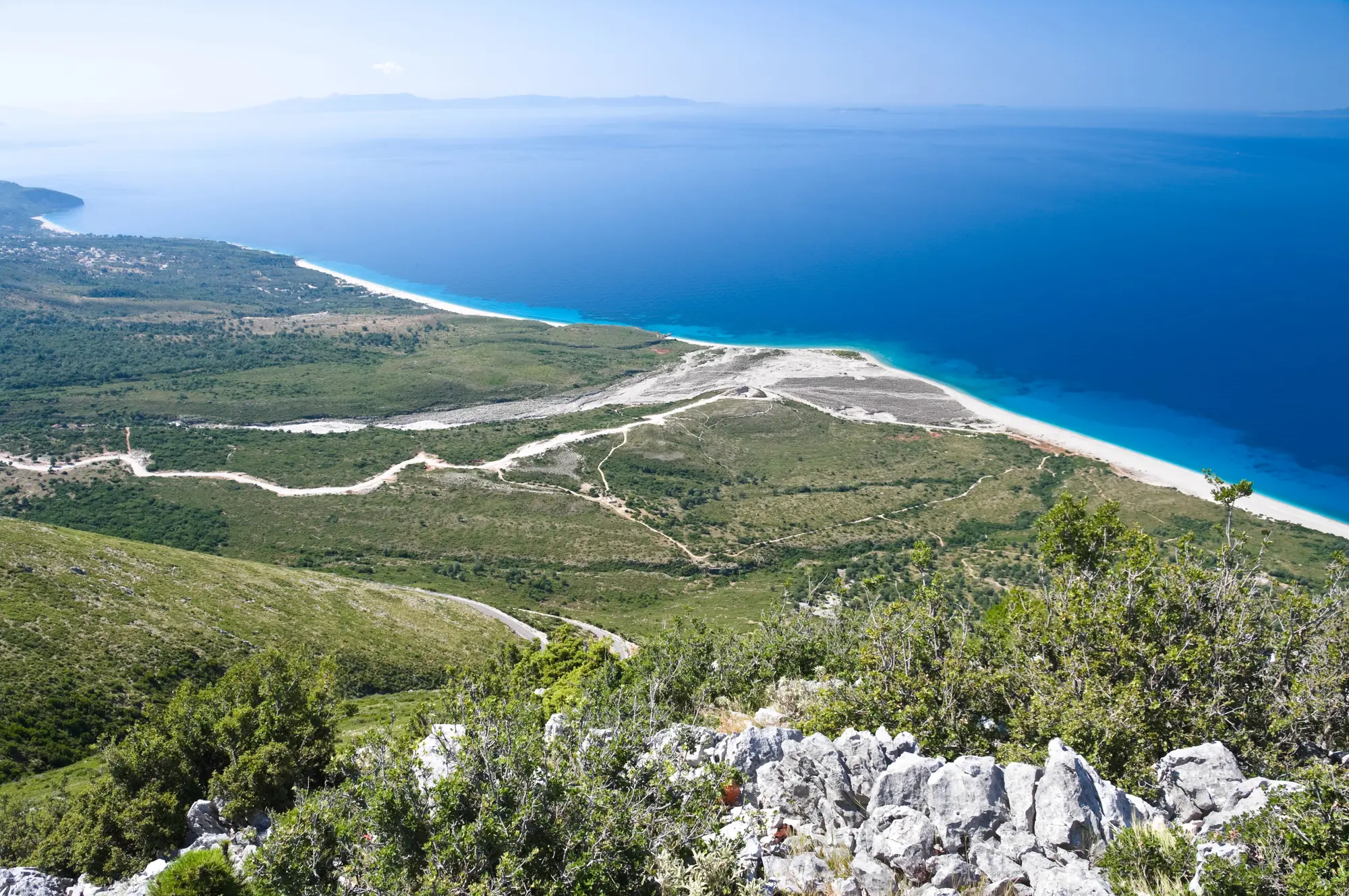 View from mountain road in Albania of green fields, white beaches and the deep blue ocean on my way to Drymades Beach in Albania.