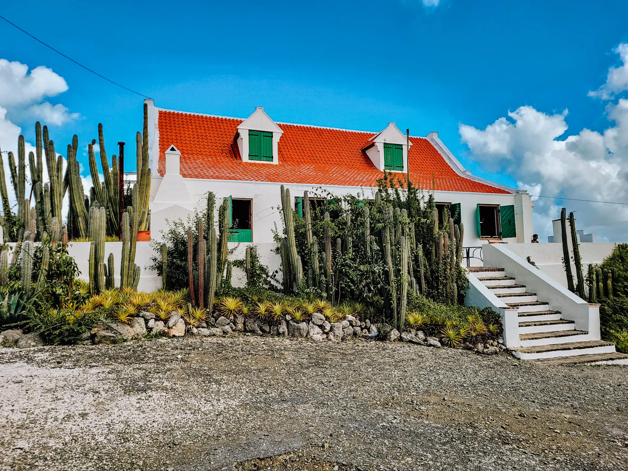 White colonial style plantation house with orange roof and green shutters, surrounded by cacti, Landhuis Jan Kok, things to know before visiting Curacao for the first time.