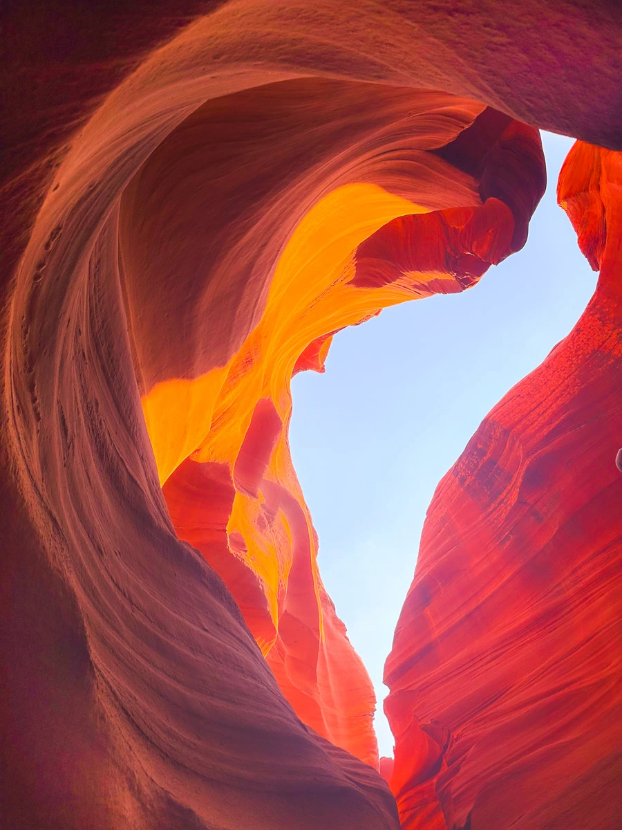 Light shining through an opening in the sandstone formations in Antelope Canyon Arizona, making it glow in shades of red, orange and brown, during a Lower Antelope Canyon Tour Review.
