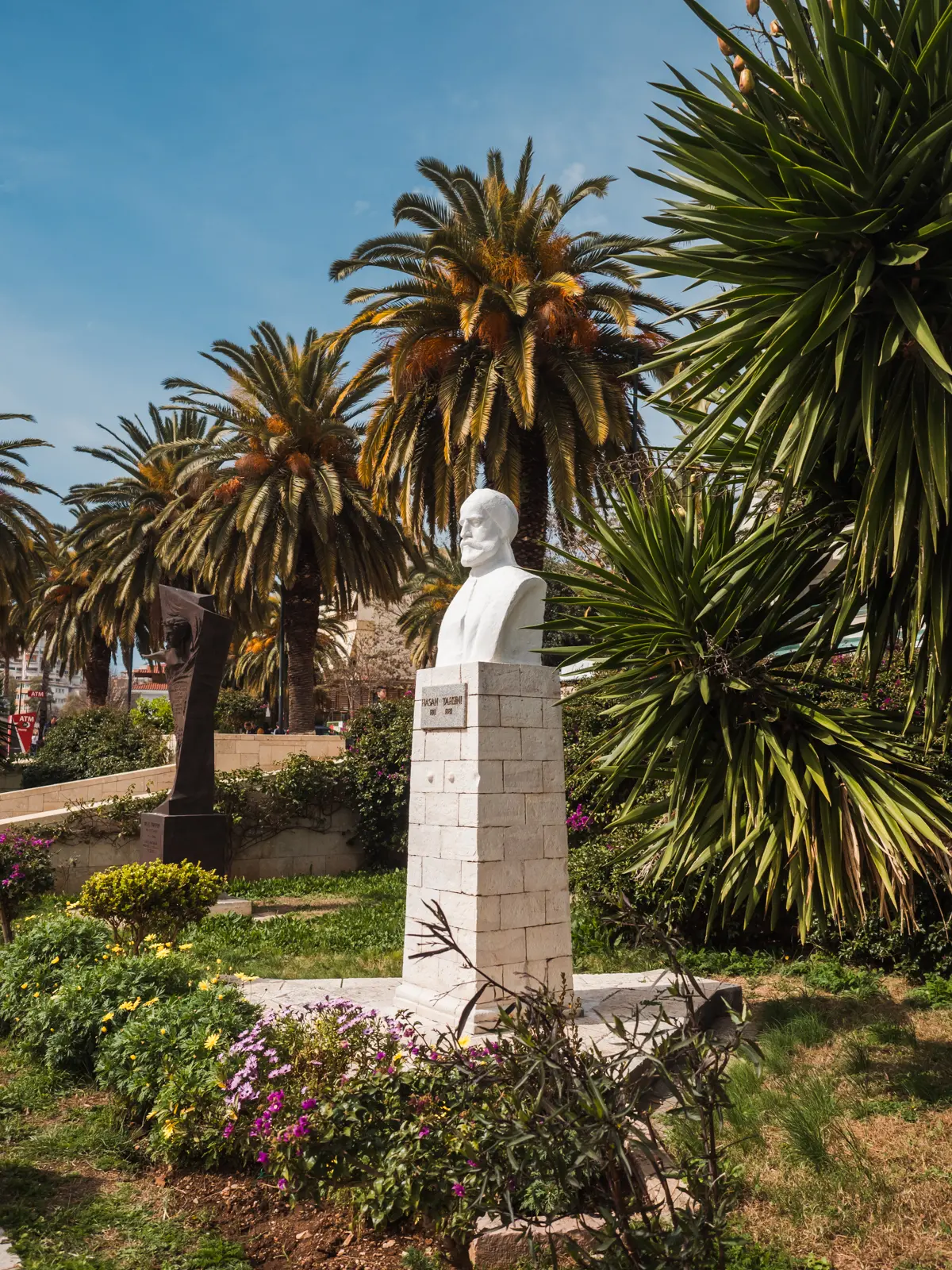 White Hasan Tahsini Monument surrounded by large palm trees on a sunny day along the promenade in Sarand&euml;, Albania.