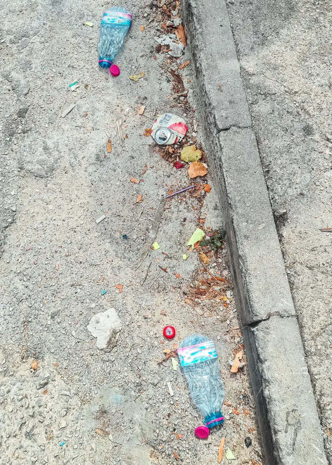 Two crushed plastic water bottles and a soda can on the side of the road in Saranda Albania. Trash problem.