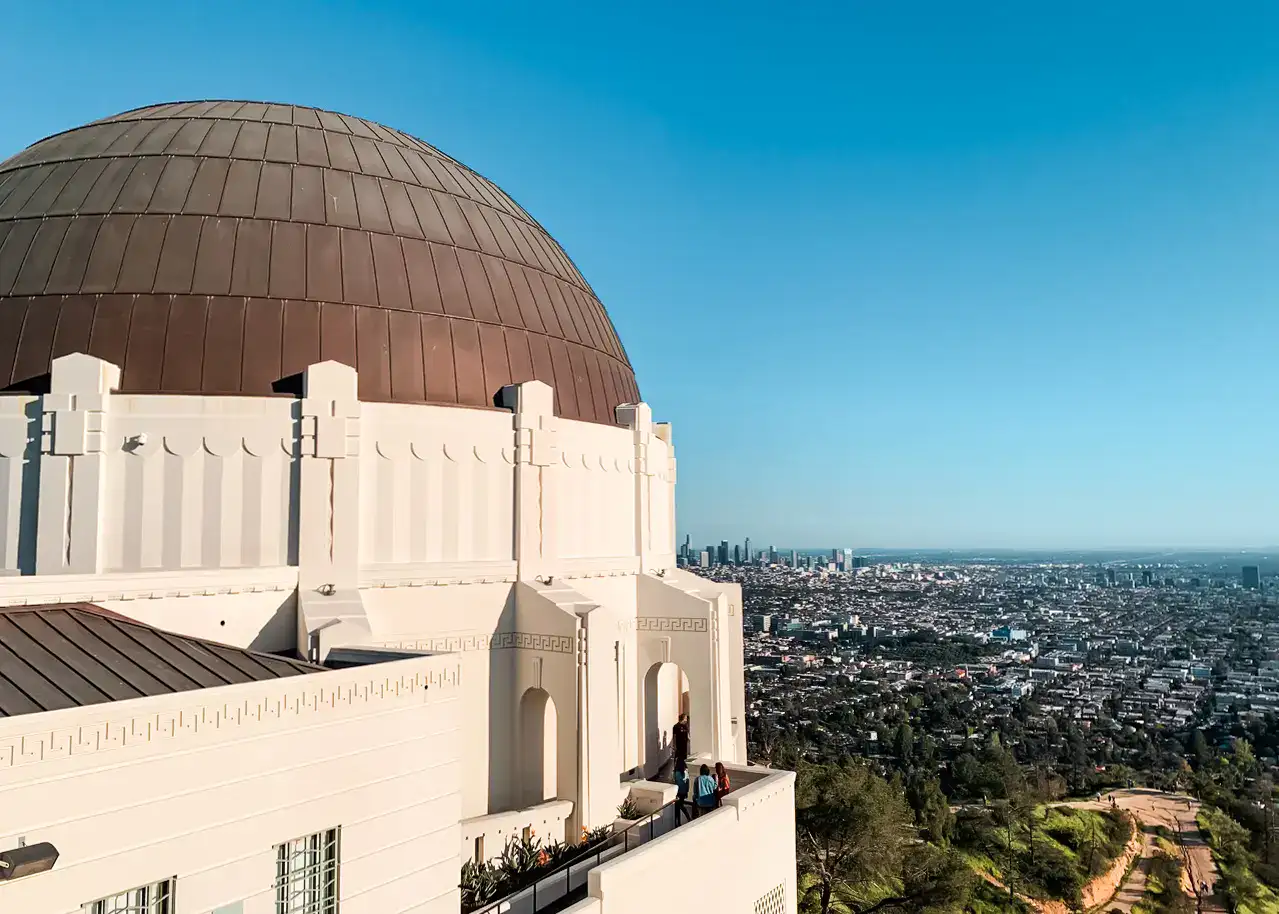 View of the white Griffith Observatory with a brown dome and Downtown LA in the background, one of the best things to do during a 3-day Los Angeles Itinerary.