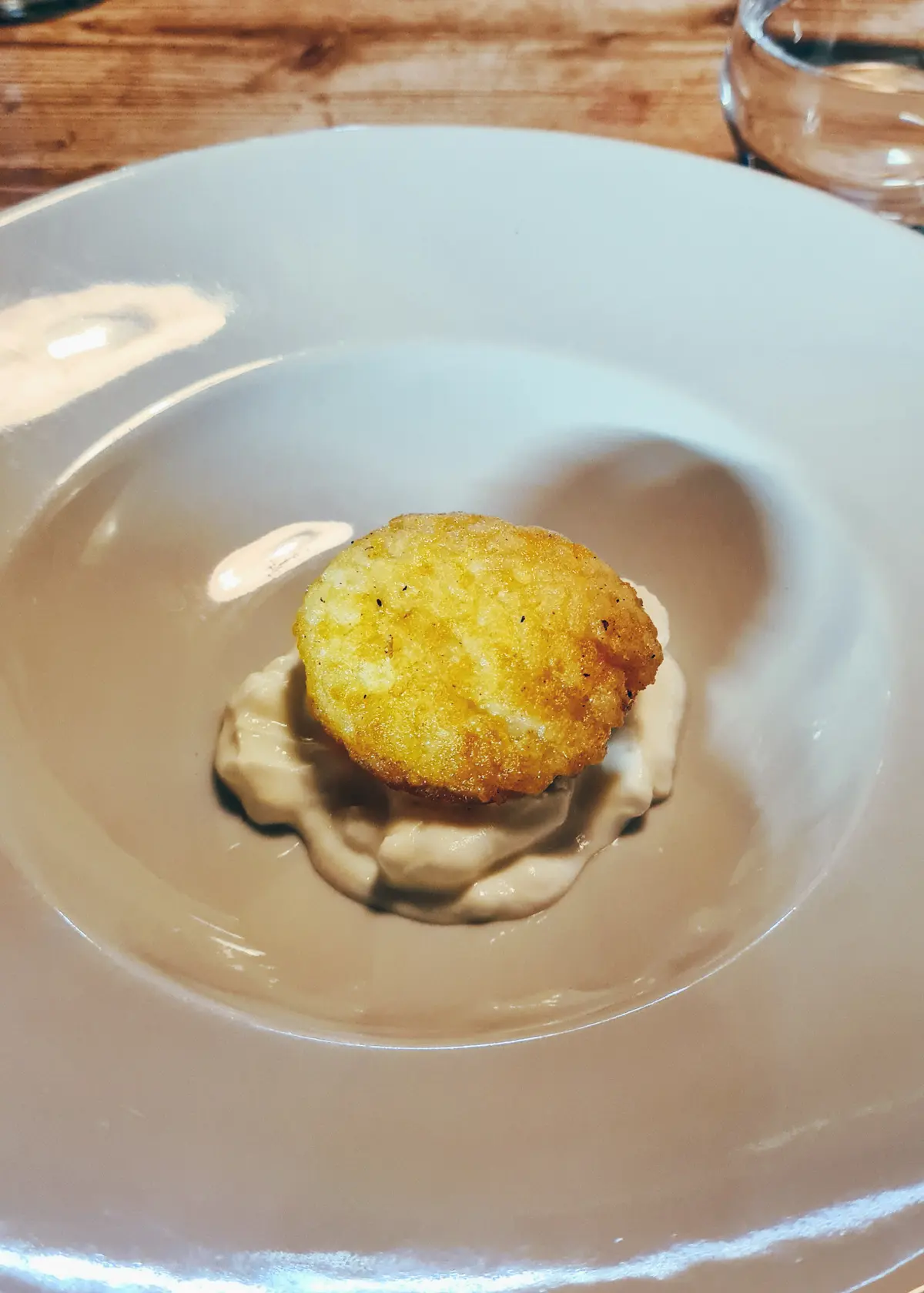 Fried rice ball on sour creme in a white bowl at Mullixhiu in Tirana.