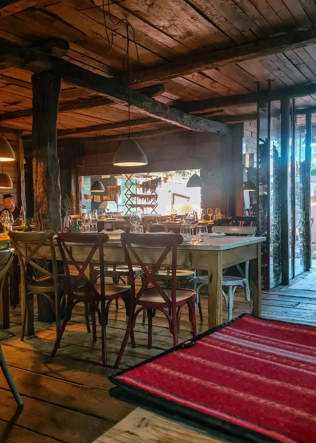 Six wooden chairs around an old wooden table in an old wooden house with pasta drying in the background and several plates and wine glasses on the table at Mullixhiu Restaurant in Tirana, Albania.