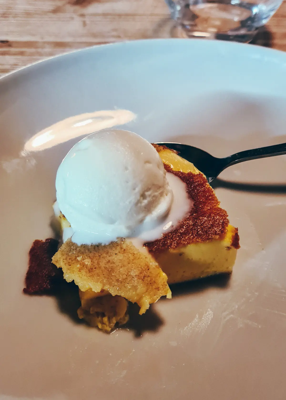 Square slice of milk cake topped with a round scoop of ice cream on a white plate, the dessert during a 7-course tasting menu dinner at Mullixhiu.