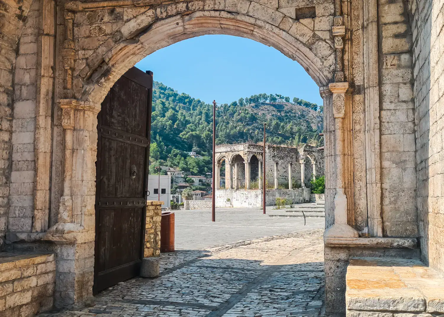 Arched stone gate in a stone wall around the ruins on a old stone manor house with arches, in Berat Albania.