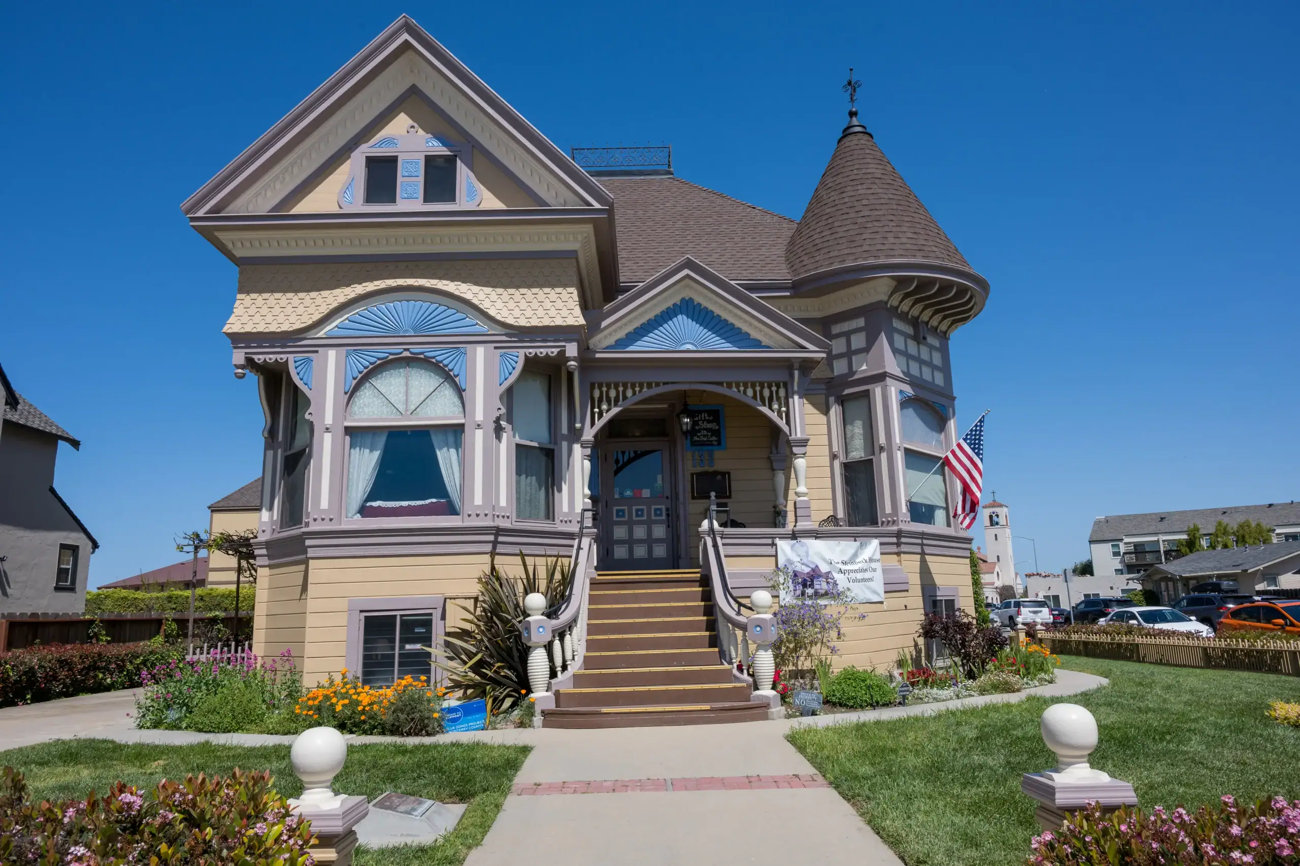 The ornate Art Nouveau Steinbeck House, beige with light blue details, small turret on the right side, brown stairs and entrance in the middle, seen on a sunny day in Big Sur on a road trip from Los Angeles.
