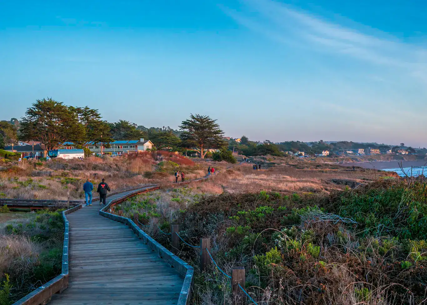 Four people walking in the distance on the wooden Moonstone Beach Boardwalk, a stop on the road from LA to Big Sur.