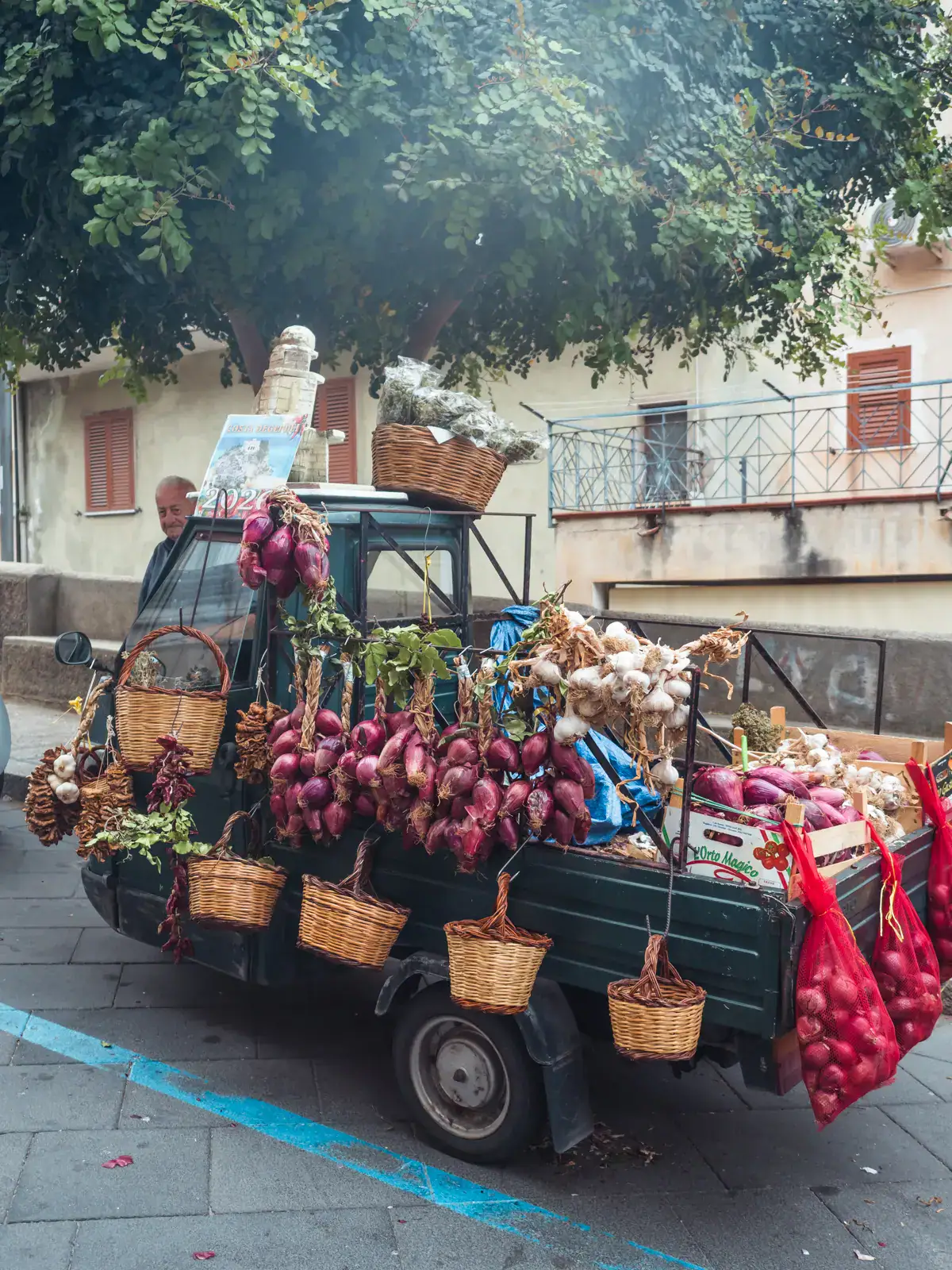 Small black truck decorated with red onions and other vegetables, one of the top things to see in Tropea, Italy.