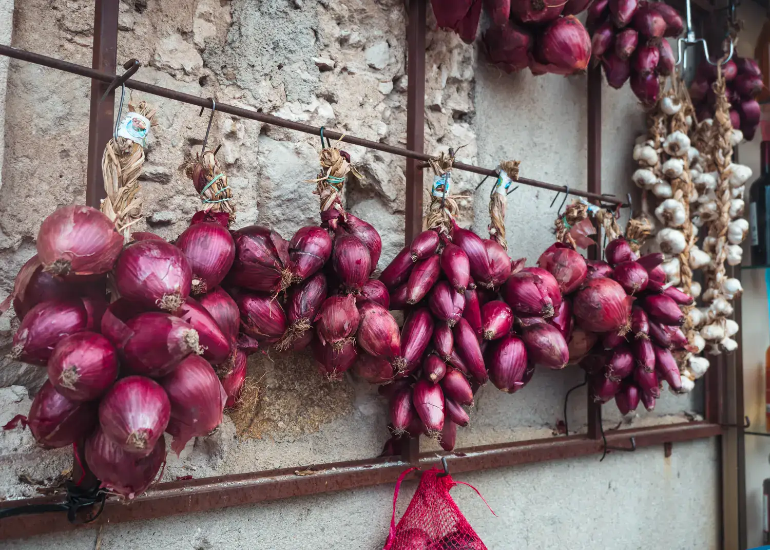 Bunches of red onion hanging on a crumbling wall in Tropea Old Town.