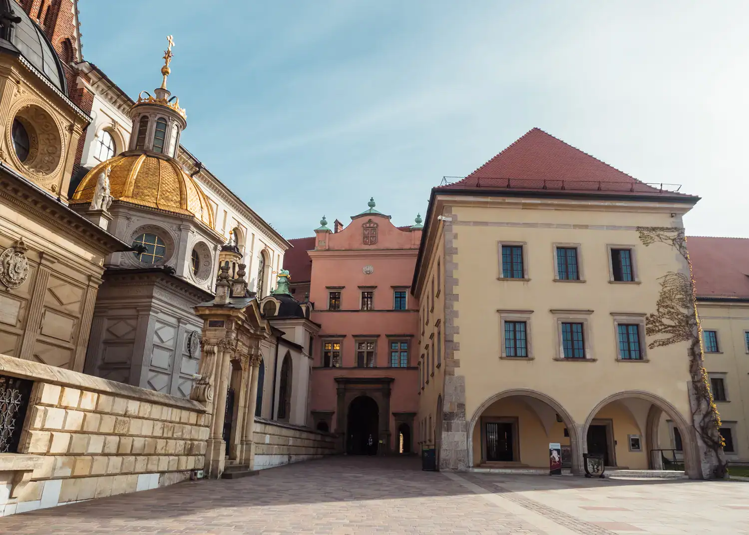 Two domes at Wawel Cathedral with many different architectural styles, Wawel Castle in the background on a sunny day, see why Krakow is one of the best European cities to visit in October.