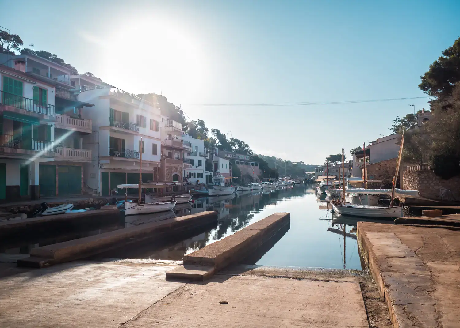 View of concrete boat ramps and white buildings in Cala Figuera Harbor on a sunny morning, why Mallorca is one of the best European destinations to visit in October.