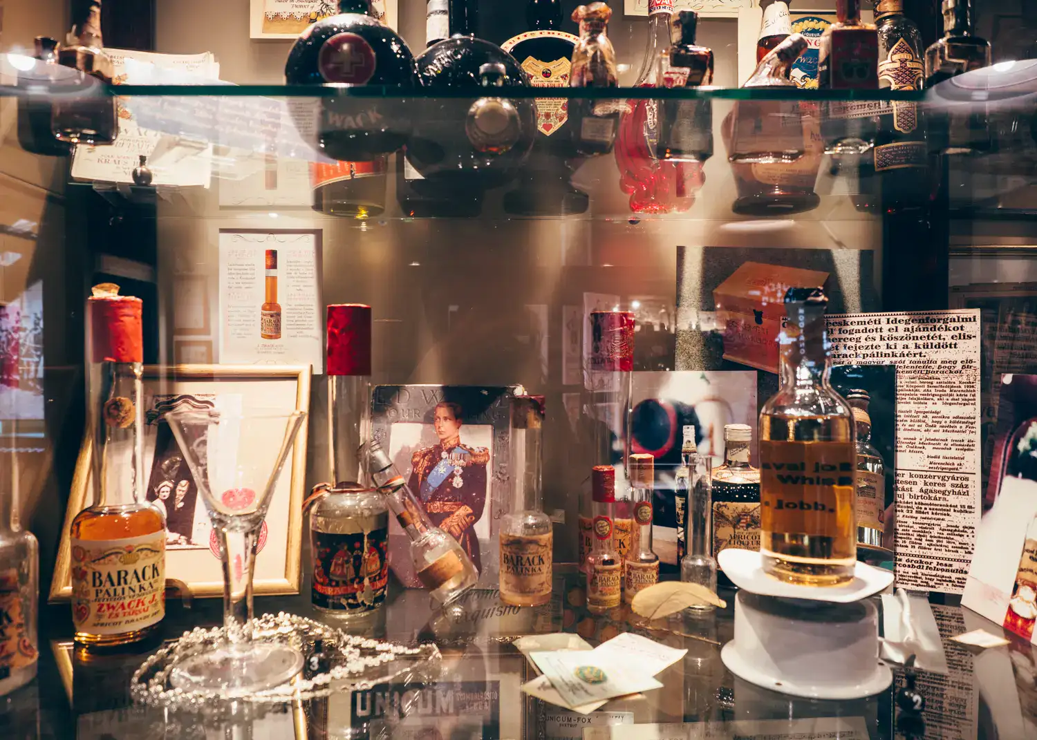 Glass shelves with old bottles, glasses, photos and information about the history of Zwack Unicum in Budapest.