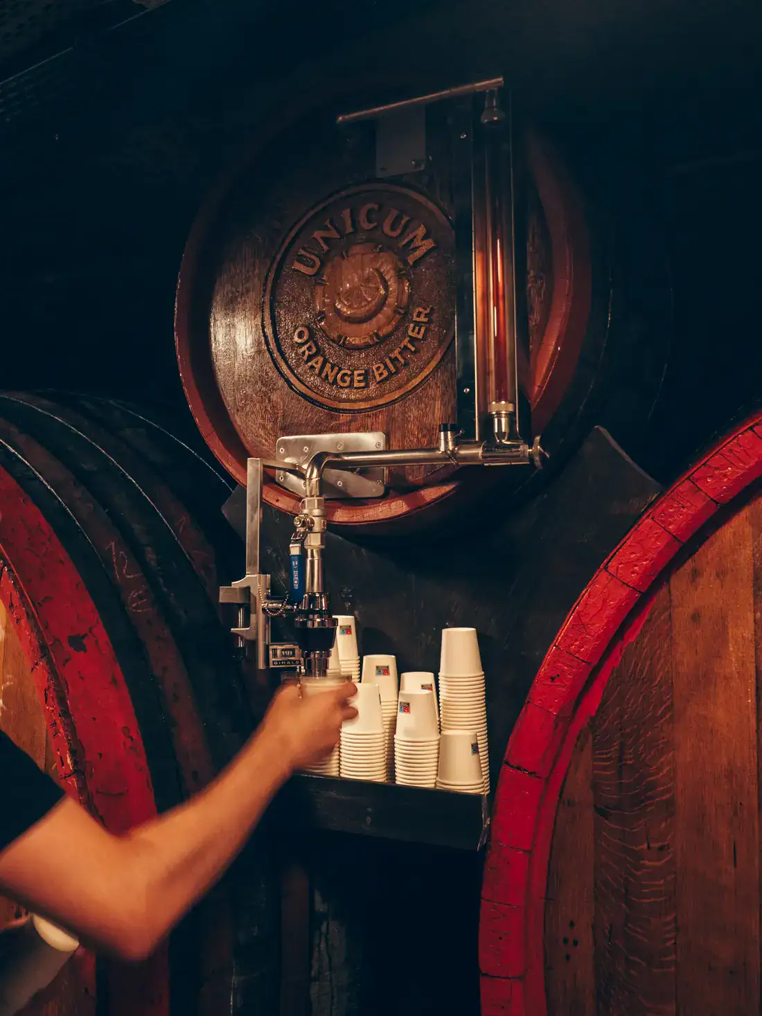 Our guide, tapping Unicum Orange Bitter from a wooden barrel with the Unicum logo during a premium tour of the Factory and Museum in Budapest.