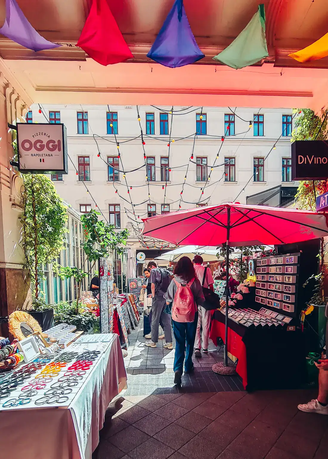 Gozsdu Weekend Market, set up in a passage with tables on each side and a red umbrella, in the Jewish Quarter Budapest.