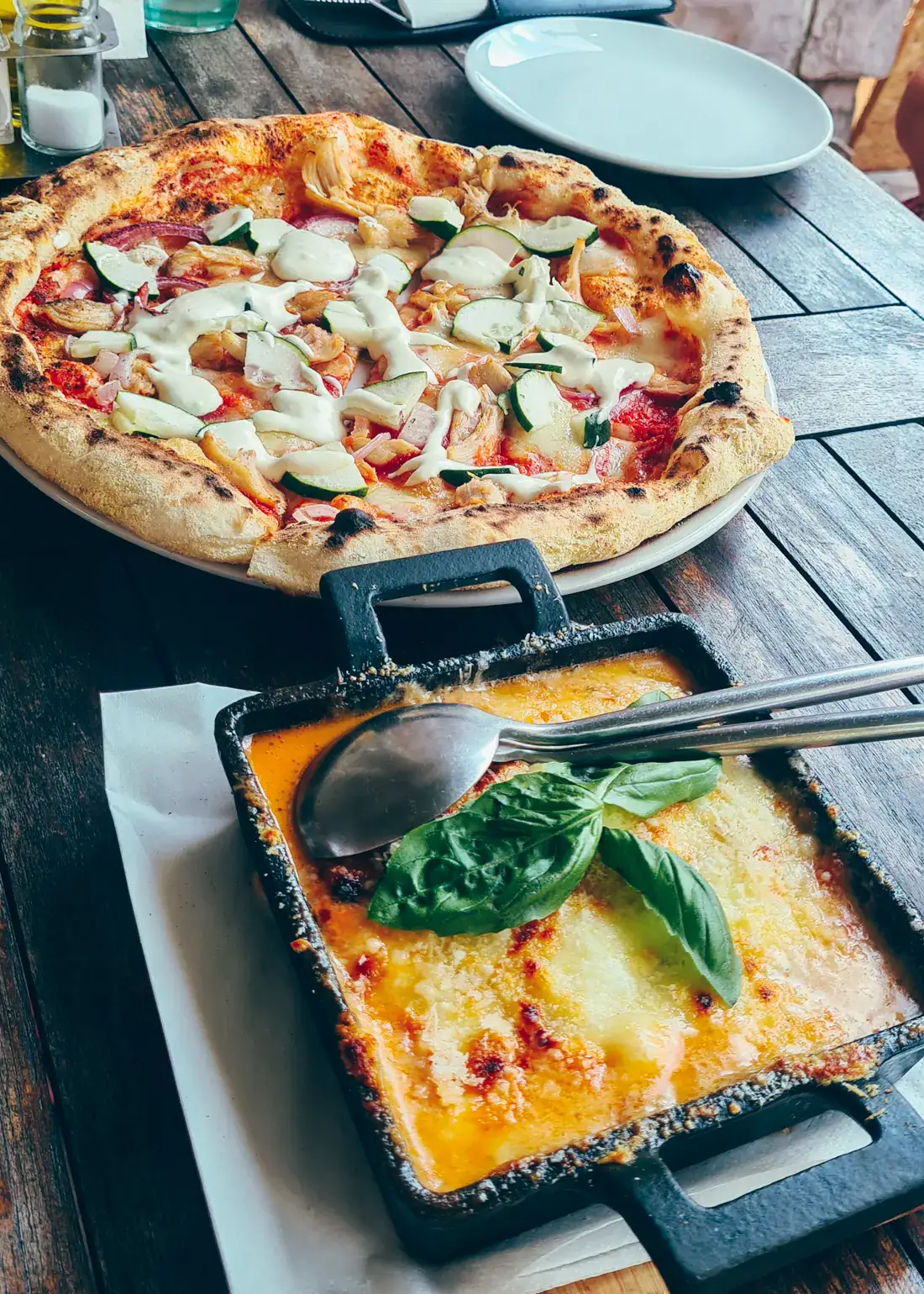 Eggplant Parmigiana in a square, black dish, gyro pizza topped with cucumber in the background on a black table at one of the best restaurants in Tivat.