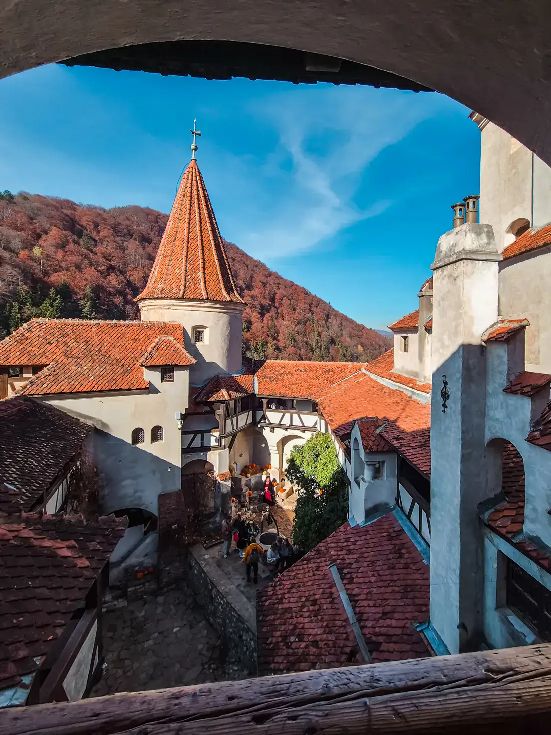 View out of a arched opening in Bran Castle, looking out over the small courtyard and turret with orange roof on a sunny day in Transylvania.