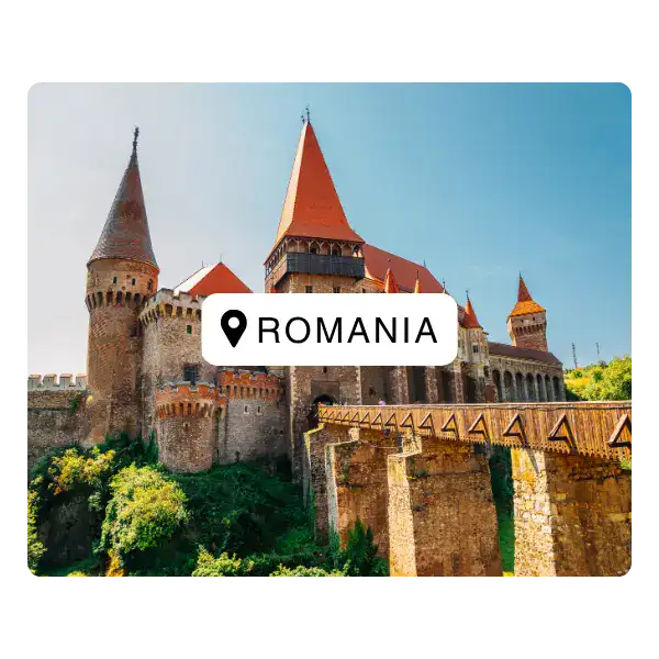 Brown stone castle with orange roof and turrets against a blue sky in Romania